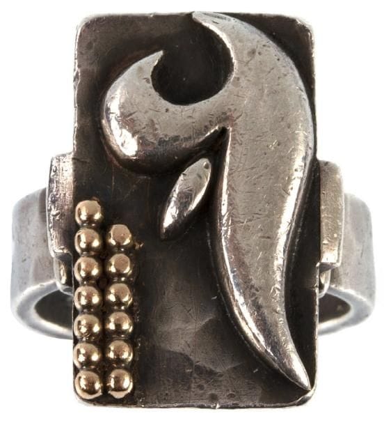 Jean DESPRÉS (1889-1980)
Bague moderniste en argent et or.  L'épaisse plateforme, à la tranche chanfreinée et à surface entièrement martelée, reçoit en décor des applications de forme libre et une double rangée de sphères en or.  L'anneau, également martelé, est maintenu sur la plateforme par des motifs simulant des attaches.  Signée du poinçon de Maître Orfèvre et porte le poinçon de titre sur l'anneau.  Poids : 13 g. Provenance : Ancienne collection icaunaise, oeuvre acquise directement auprès de l'artiste.
