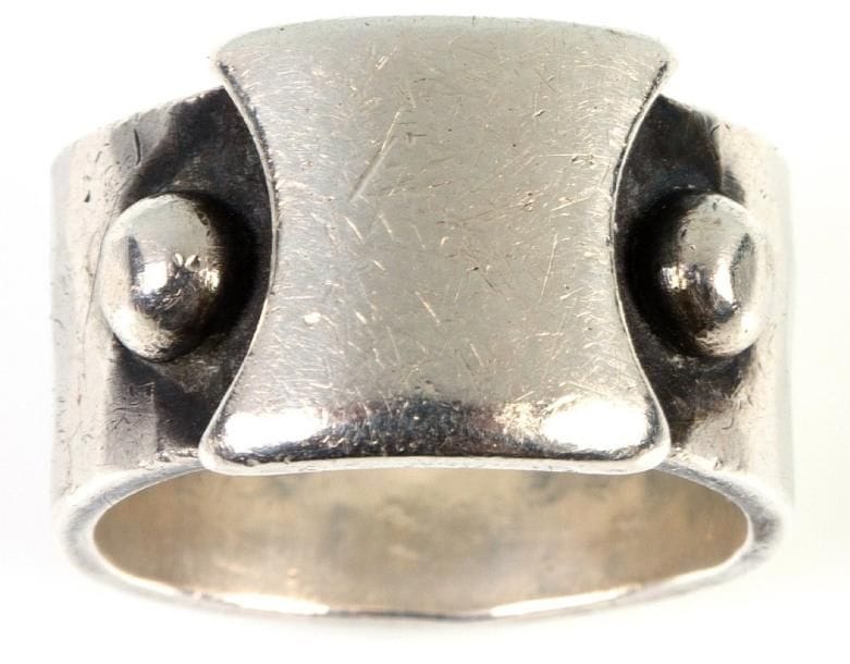 Jean DESPRÉS (1889-1980)
Très rare bague moderniste en argent.  Le large anneau martelé reçoit un décor central en application d'une plaquette échancrée lisse ornée latéralement de deux demi-sphères.  Signée du poinçon de Maître Orfèvre et porte le poinçon de titre sur l'anneau.  Poids : 12 g. Provenance : Ancienne collection de Madame X. à Avallon (Yonne), oeuvre acquise directement auprès de l'artiste.