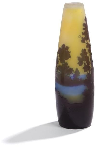 Émile GALLÉ (1846-1904)
Vase fuselé.  Épreuve de tirage industriel en verre multicouche dégagé à l'acide au décor bleu intense, outremer et violet, d'un paysage lacustre avec un arrière-plan de montagne, sur fond jaune opalescent.  Signé GALLE en gravure dans le décor vers la base.  Hauteur : 18 cm
