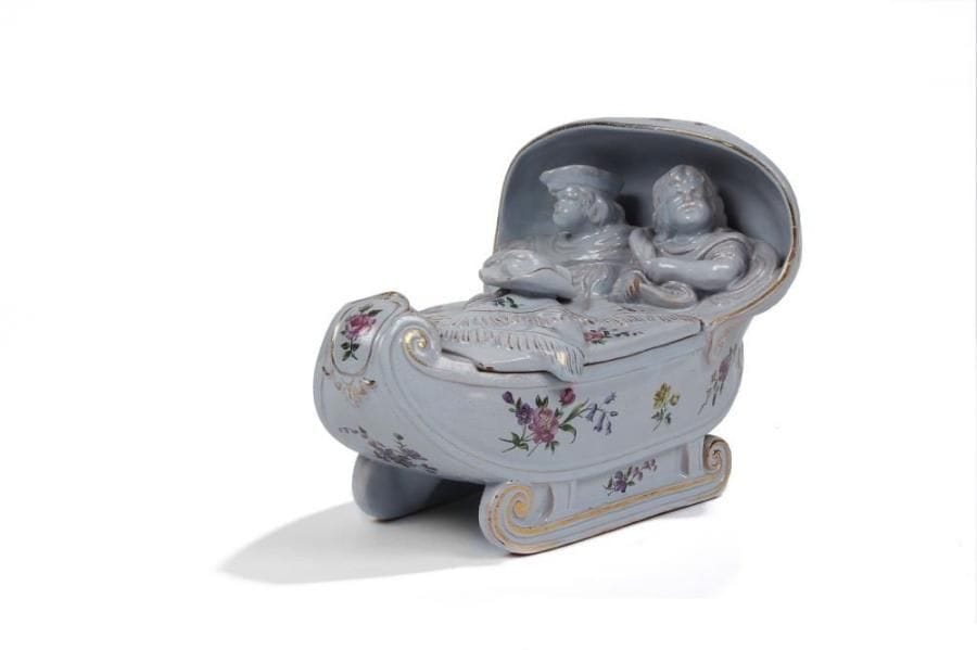 Émile GALLÉ (1846-1904)
Enfants dans un traîneau. Boîte en ronde-bosse réalisée en faïence émaillée gris au décor floral polychrome.  Rehauts de dorure sur les arêtes et dans le décor.  Quelques usures d'émail éparses.  Vers 1880.  Signé Emile GALLE à Nancy - Déposé en relief sous la base.  20 x 31 x 20 cm