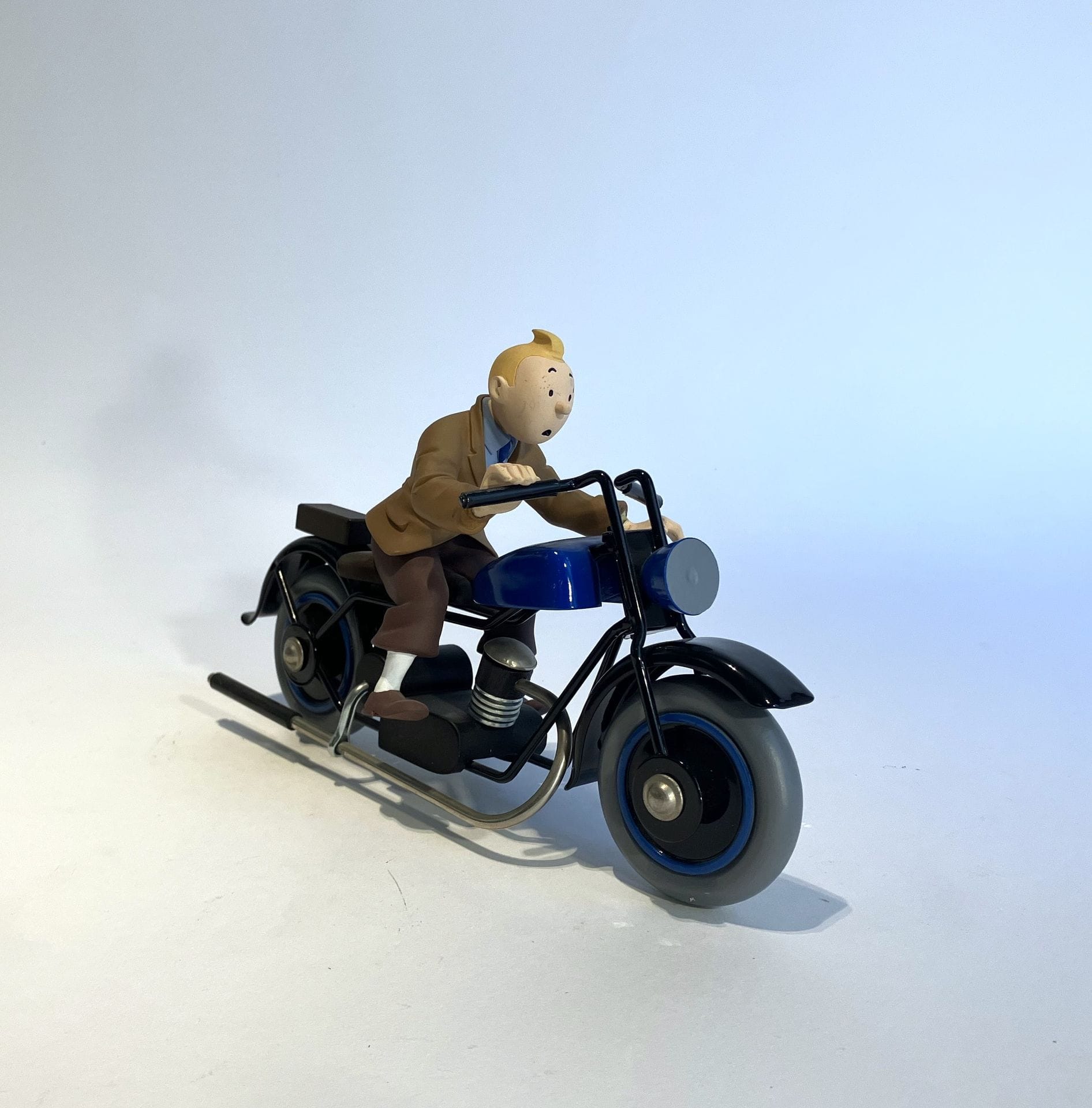 THE OTTOKAR SCEPTRE 
Tintin on his motorcycle
Subject in resin and polychrome metal. Editions Moulinsart. Created by Michel Aroutcheff in 2000. 
L. 25 cm - H. 13.5 cm 
(The left hand needs refixing).