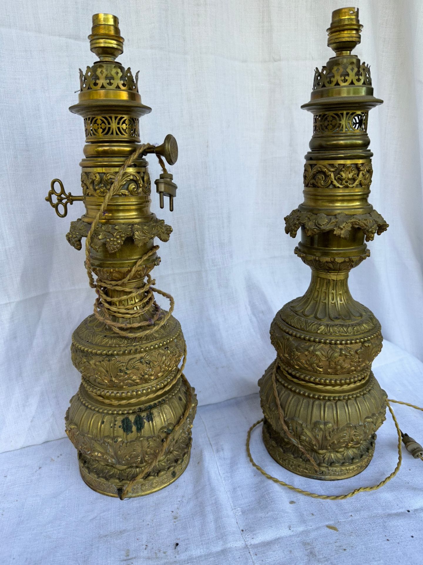 Paire de lampes à huile en bronze et laiton, le fût à double balustre à décor de pampres et de rinceaux.