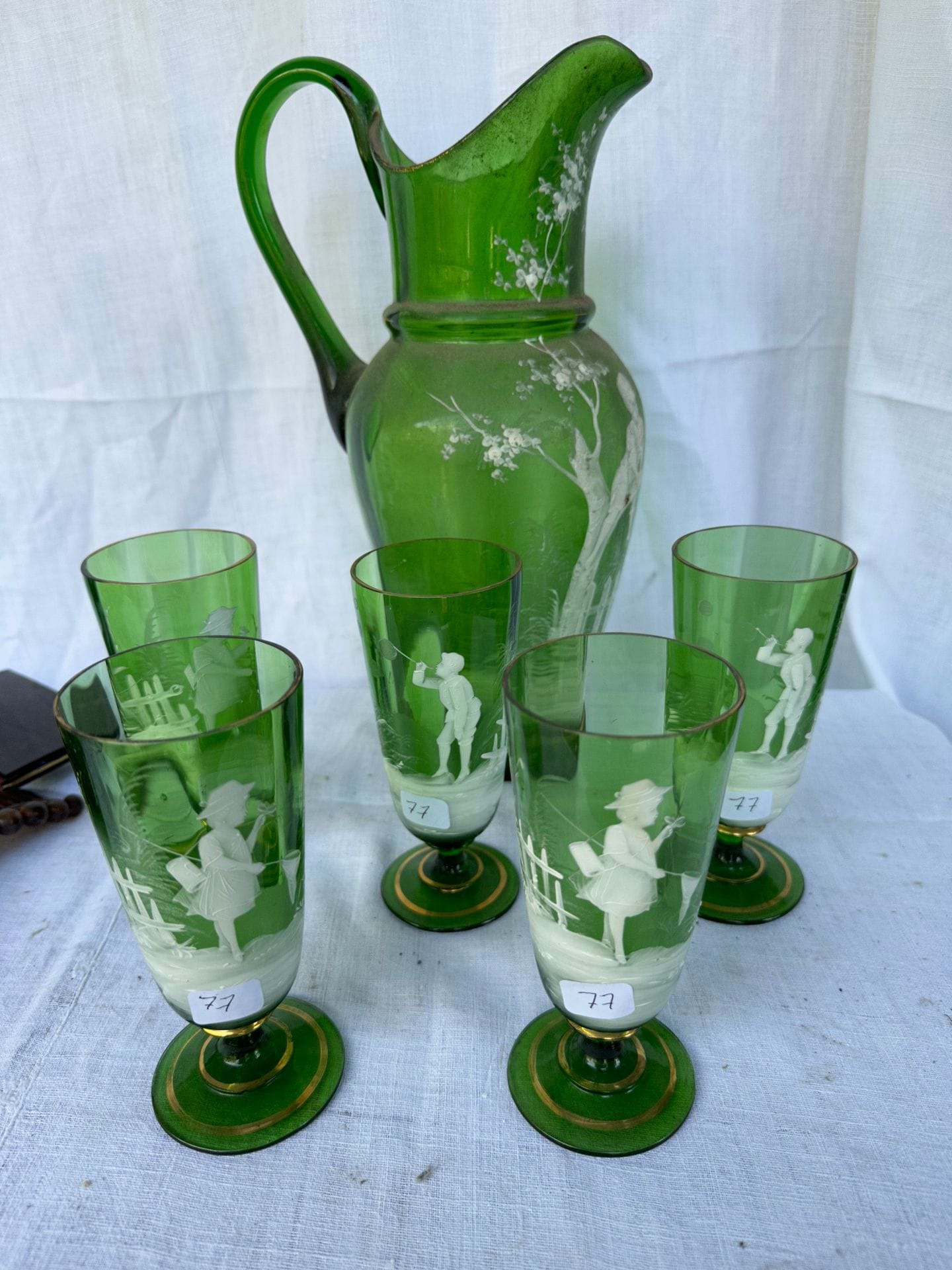 ALLEMAGNE
5 verres et une carafe en verre teinté vert à décor émaillé blanc de personnages.