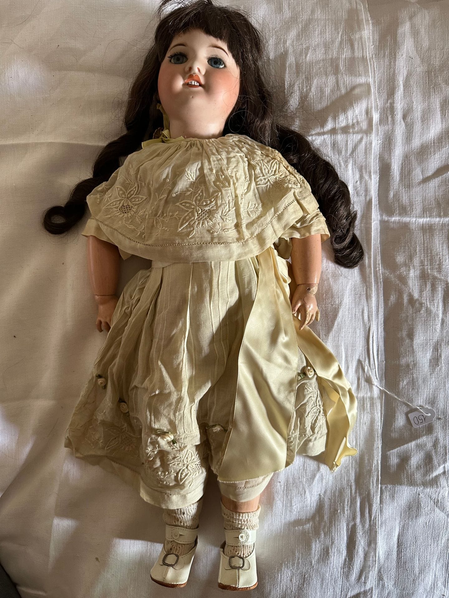 S.F.B.J.
Doll n°22, porcelain head, fixed blue eyes, mouth open over 4 teeth. Body in articulated composition. Dress in beige silk, embroidered. 
H. 60 cm