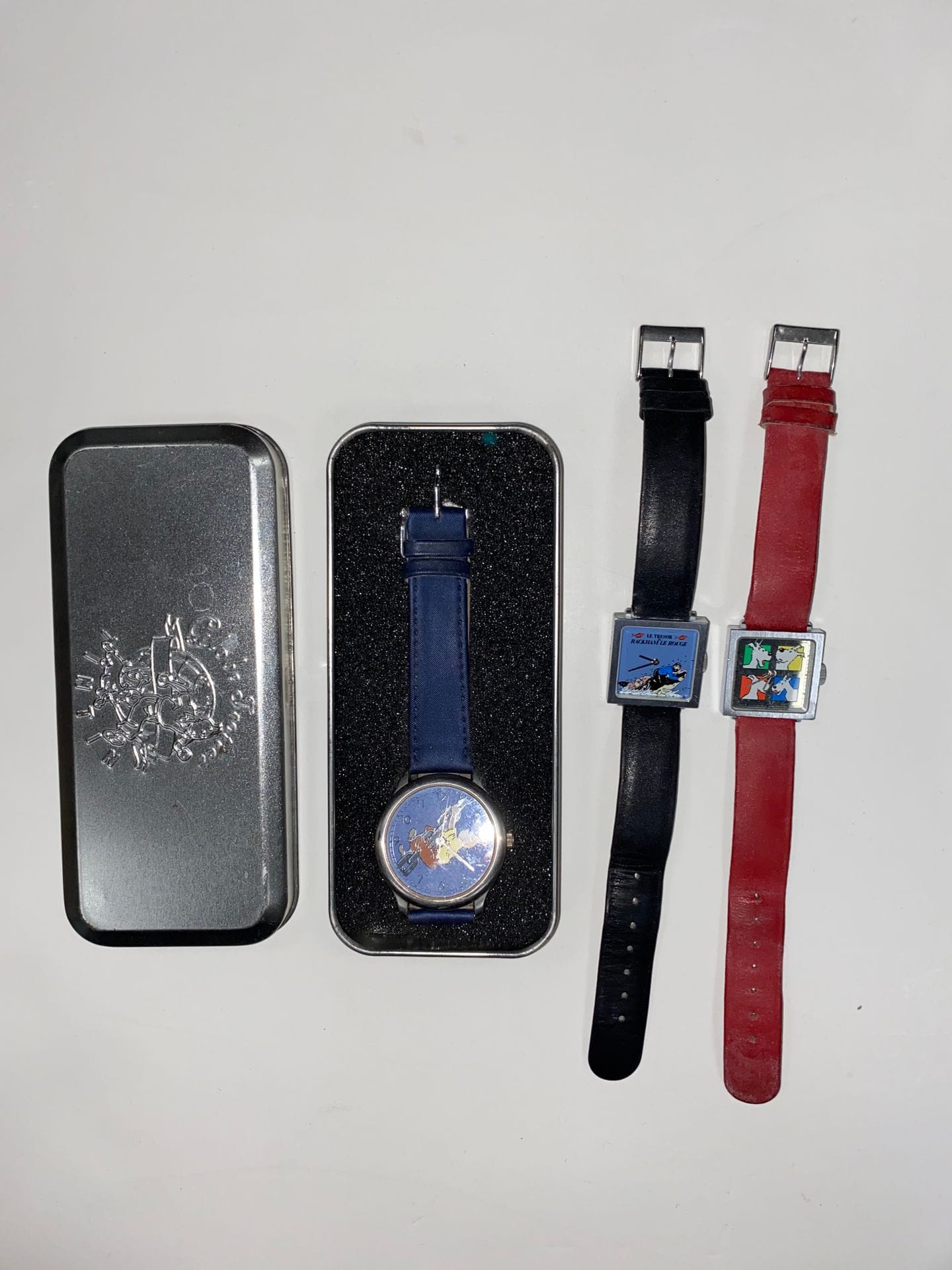 TINTIN
Set of 4 watches: 
- Tintin watch, dark blue bracelet. In original metal box. Tintin GlobeTrotter series.
- Le Trésor de Rackham le Rouge Captain Haddock Tintin watch, black imitation leather strap. 
- Snowy watch, red imitation leather strap. 
- Captain Haddock watch with insults, black bracelet.