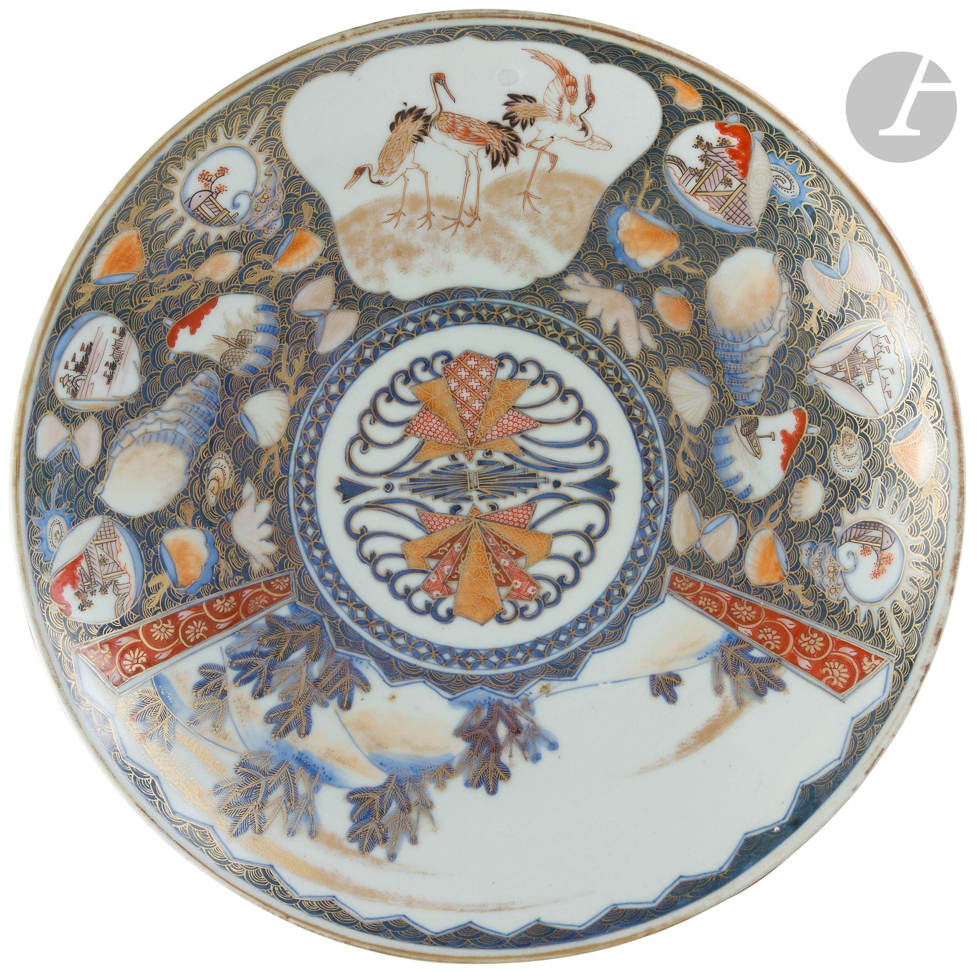 Japan  
Circular porcelain bowl decorated with blue, red and gold Imari fans in the center and on the wing with three cranes and a landscape inscribed in two fan-shaped reserves in a shell surround on a blue background decorated with gold waves. 
19th century.  
L. 34 cm.