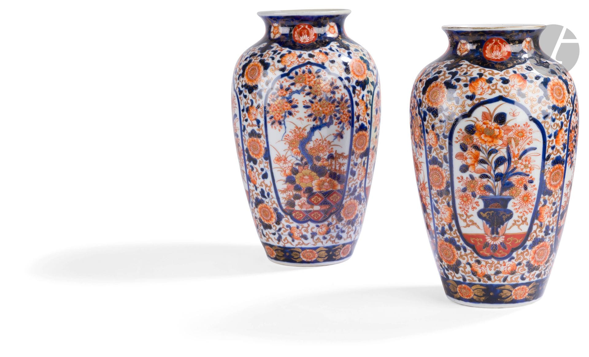 Japon 
Paire de vases en porcelaine à décor bleu, rouge et or Imari de vases fleuris et arbustes dans des réserves. 
XIXe siècle.  
H. 25 cm. 
Restaurations à l’un.