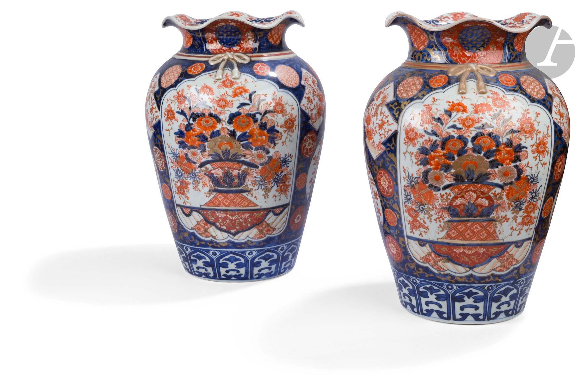 Japon 
Paire de vases oblongs à col ondulé en porcelaine à décor bleu, rouge et or Imari de jardinières fleuries, prunus, pivoines et lions dans des réserves sur fond bleu. 
XIXe siècle.  
H. 47 cm.