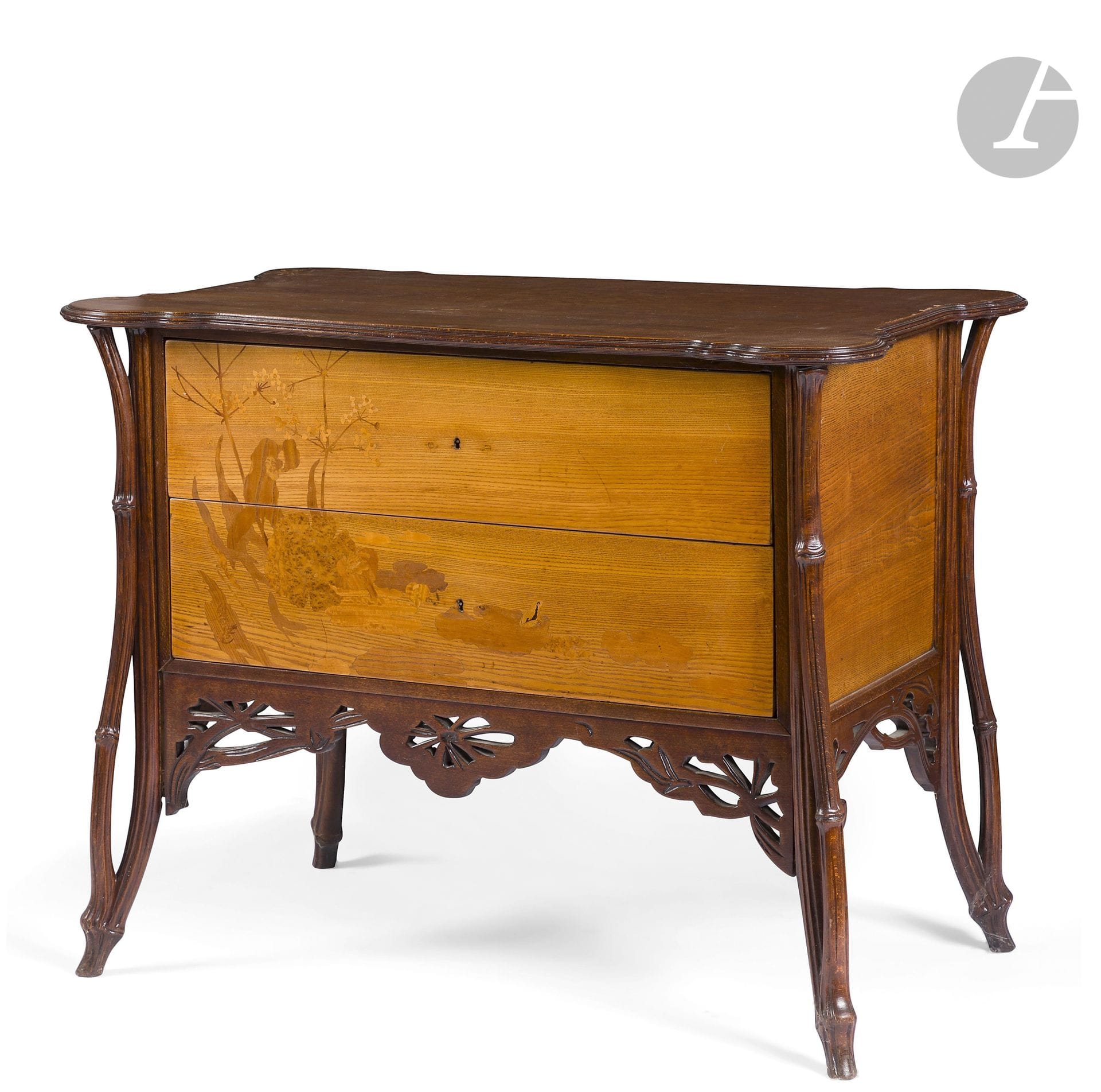 ÉMILE GALLÉ (1846-1904)
La Berce des prés, circa 1902/03
Exceptionnelle commode, dite Sauteuse, en placage de frêne et en hêtre sculpté et teinté. Le corps suspendu reçoit les deux tiroirs au décor en façade, de Berces des prés bordant un marais présentant des nénuphars et animé d’une grenouille, réalisé en marqueterie de bois précieux et indigènes. La ceinture ajourée et sculptée reprend le thème décoratif des ombellifères. Les quatre jambages d’angle sont traités et sculptés dans le goût arborescent. Le dessus est constitué d’un plateau chantourné en débordement. Le dos panneauté est exécuté en noyer. État et restaurations d’usage, partie centrale de la ceinture ajourée refaite. Signée GALLÉ en lettres japonisantes verticales dans le décor en marqueterie. H. 84 cm – L. 107 cm – P. 63 cm

Bibliographie :
Alastair Duncan et Georges de Bartha – Gallé Furniture – Éditions Antique Collectors’ Club, Woodbridge, Suffolk, U.K., 2012. Le dessin préparatoire et le calque d’exécution du décor en marqueterie de ce modèle de commode, deux documents conservés au Musée d’Orsay, sont reproduits page 330.