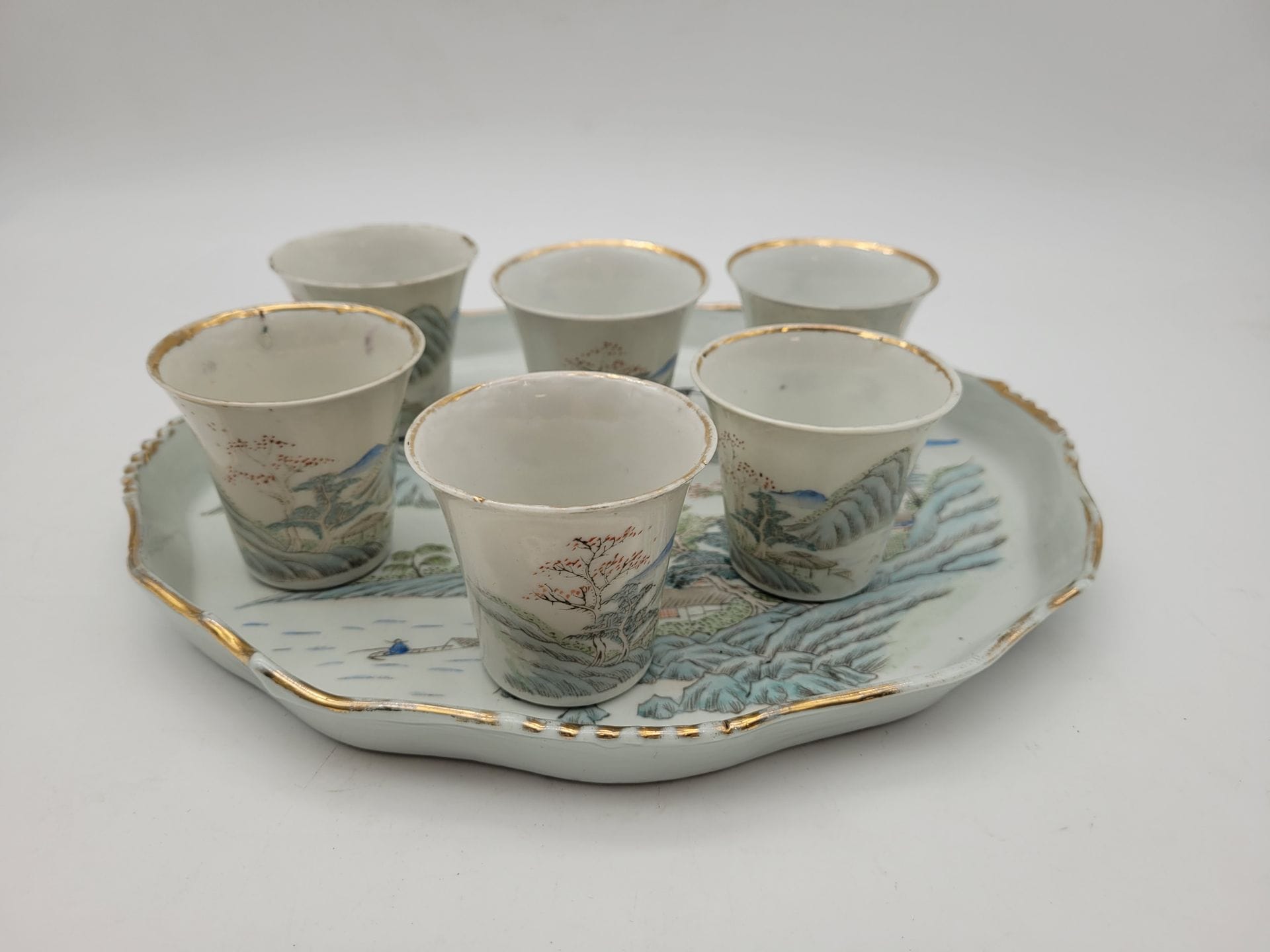 6 porcelain cups and 1 tray, China, 19th century
Decorated with landscapes and calligraphy, the tray with gilded scalloped edges. Traces of marks under the base of the cups.
H. cups: 6 cm; L. tray: 28.5 cm