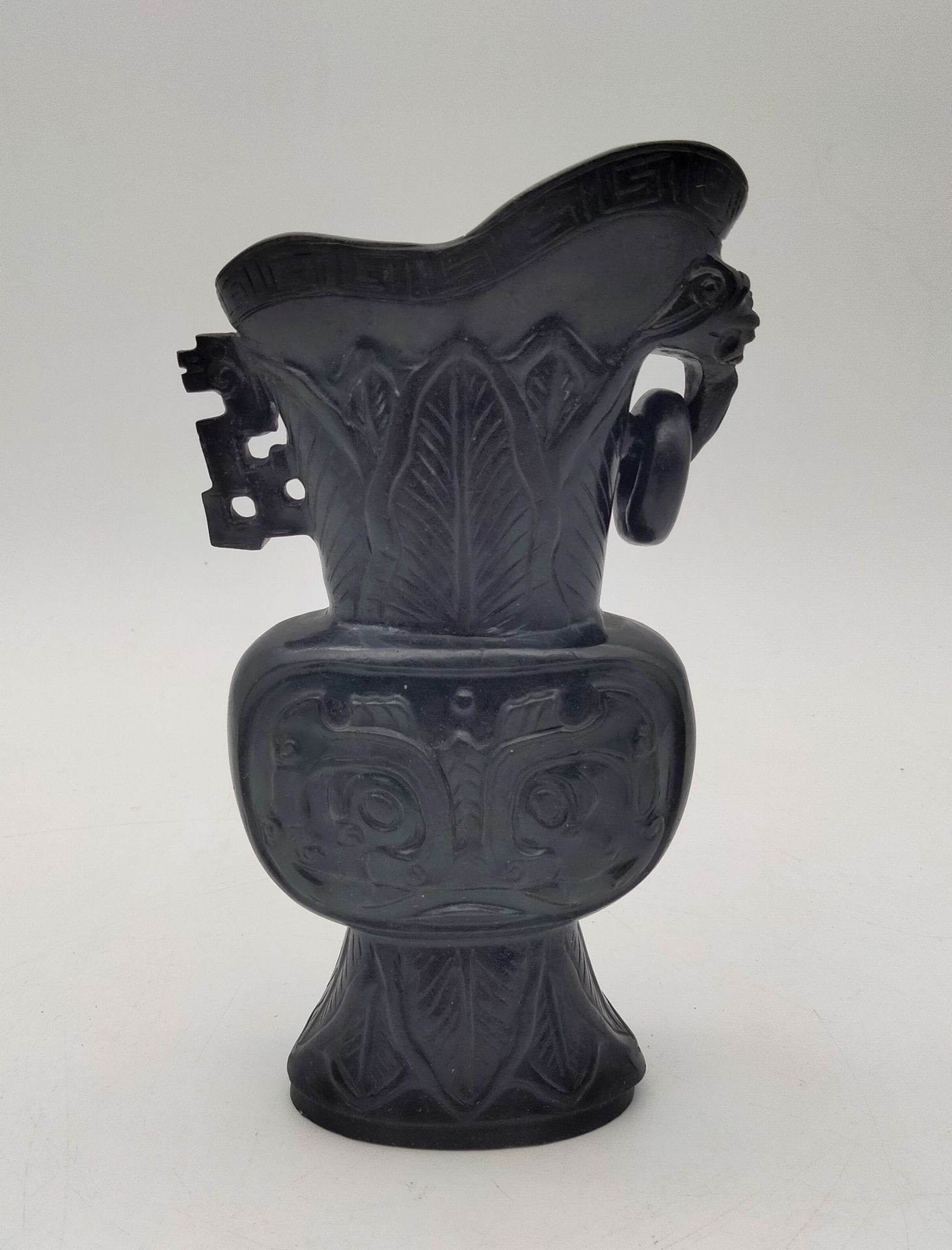 Archaic style vase in very dark green jade, China, 20th century
Decorated with taotie masks, one handle in the form of a stylized dragon and the other in the form of a chimera with a ring.
Height 15.5 cm