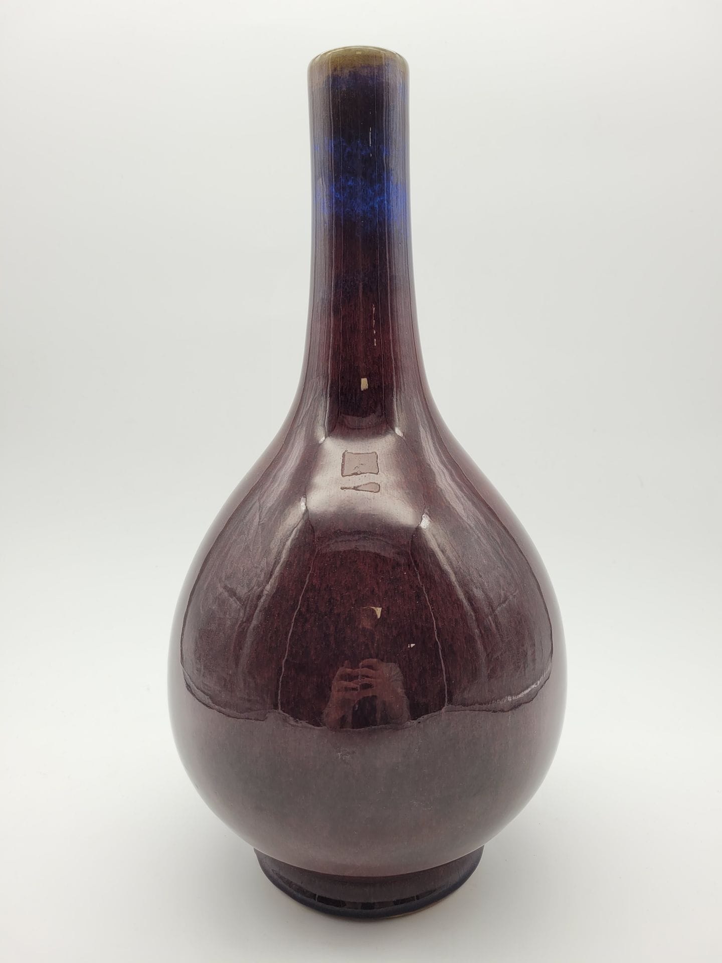Bottle vase with long tubular neck in porcelain with red flamed glaze, China, 19th century
Resting on a short foot, the slightly cracked glaze is a beautiful deep red, the top of the neck shows celadon ochre-green tones and the neck a beautiful lavender-blue color also present around the foot. The cover has been lightly lapped around the heel. Apocryphal Qianlong six-character mark in underglaze blue on the base.
Height: 39 cm