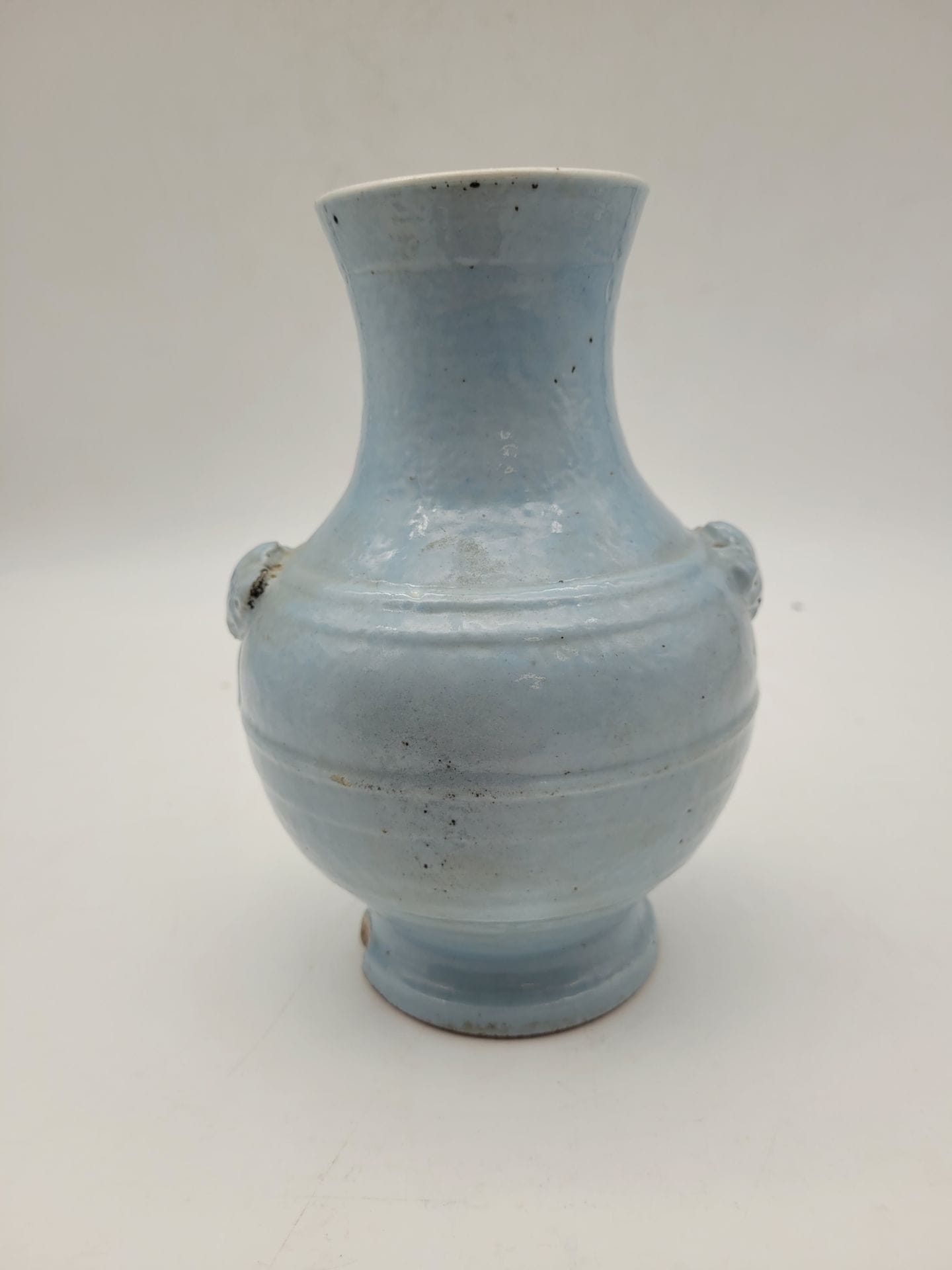 Petite vase en porcelaine, Chine, XXe siècle
A couverte bleu ciel, panse épaulée de masques. Marque aprocyphe sous la base. 
Hauteur : 18 cm
Petits éclats.
