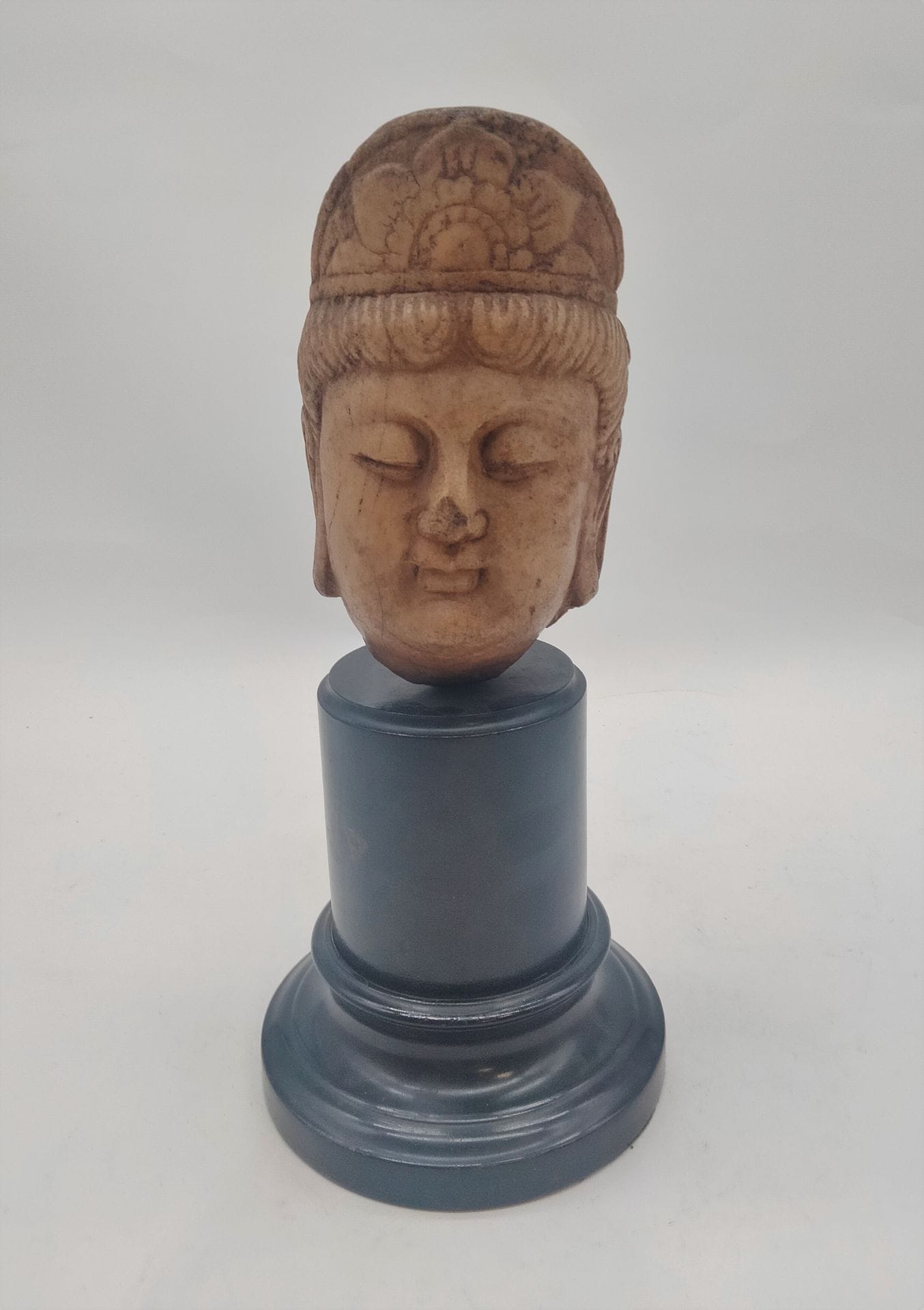 Tête de Guanyin en marbre sculptée, Chine 
Sur un socle en bois noirci. 
Hauteur de la tête : 16 cm ; hauteur totale : 30 cm 
Accidents, nez cassé.
