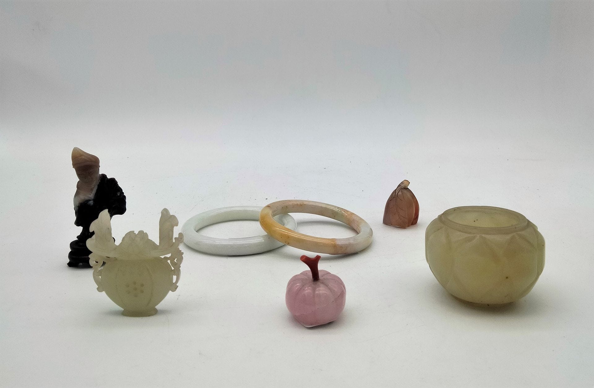 Lot de pierres dures, Chine, XXe siècle 
2 bracelets en jade (D.ext. : 7,4 cm), un petit ornement en jade (4,9 cm), 1 petit vase à facettes en jade (H : 4 cm).
On joint un élément en agate, un petit melon en quartz rose, la queue en corail et un petit personnage en  agate