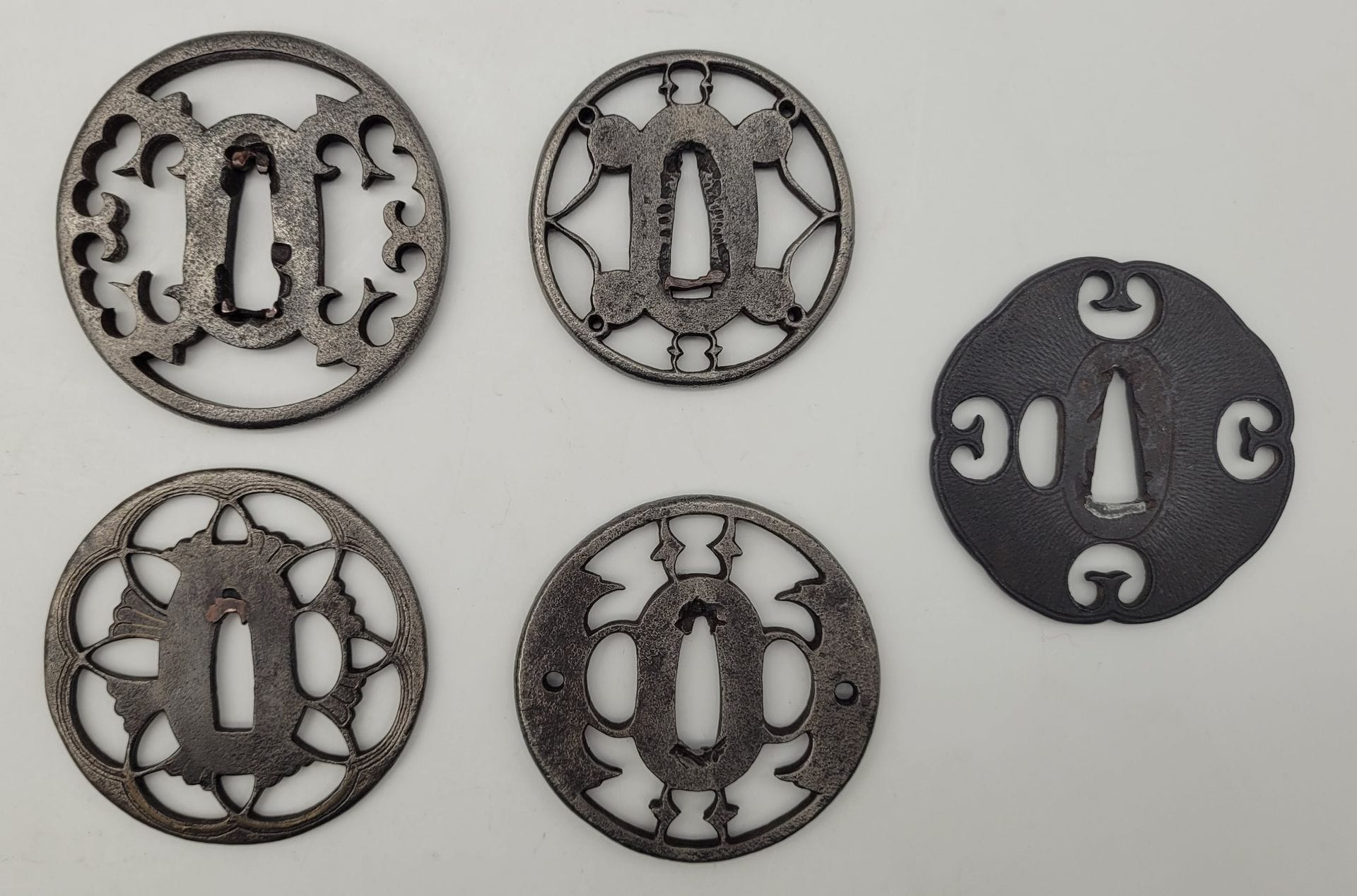 Set of five iron tsuba, Japan
Maru and kawari gata forms with openwork decoration of leaves and flowers.
Worn, missing, de-patinated.