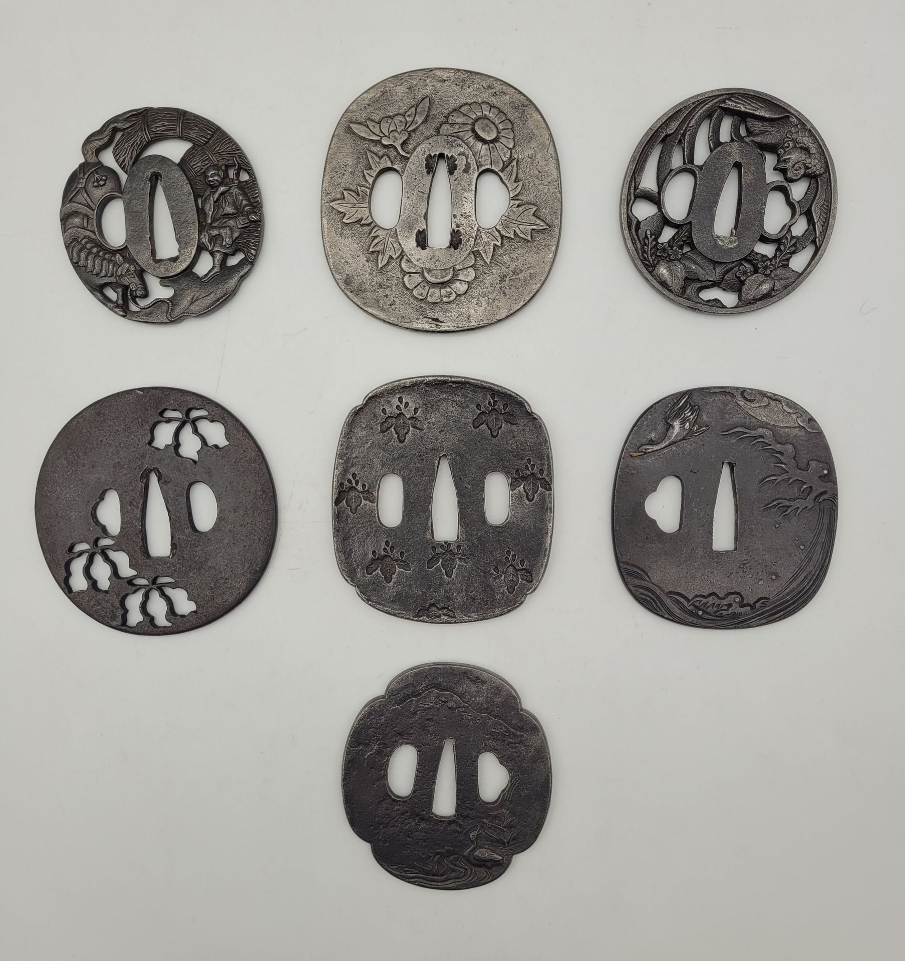 Lot de sept tsuba en fer, Japon
Formes diverses (maru, naga maru, mokko, sumi iri kaku et kawari gata)  à décors d'animaux et de végétaux.
Usures, manques, dépatinées.