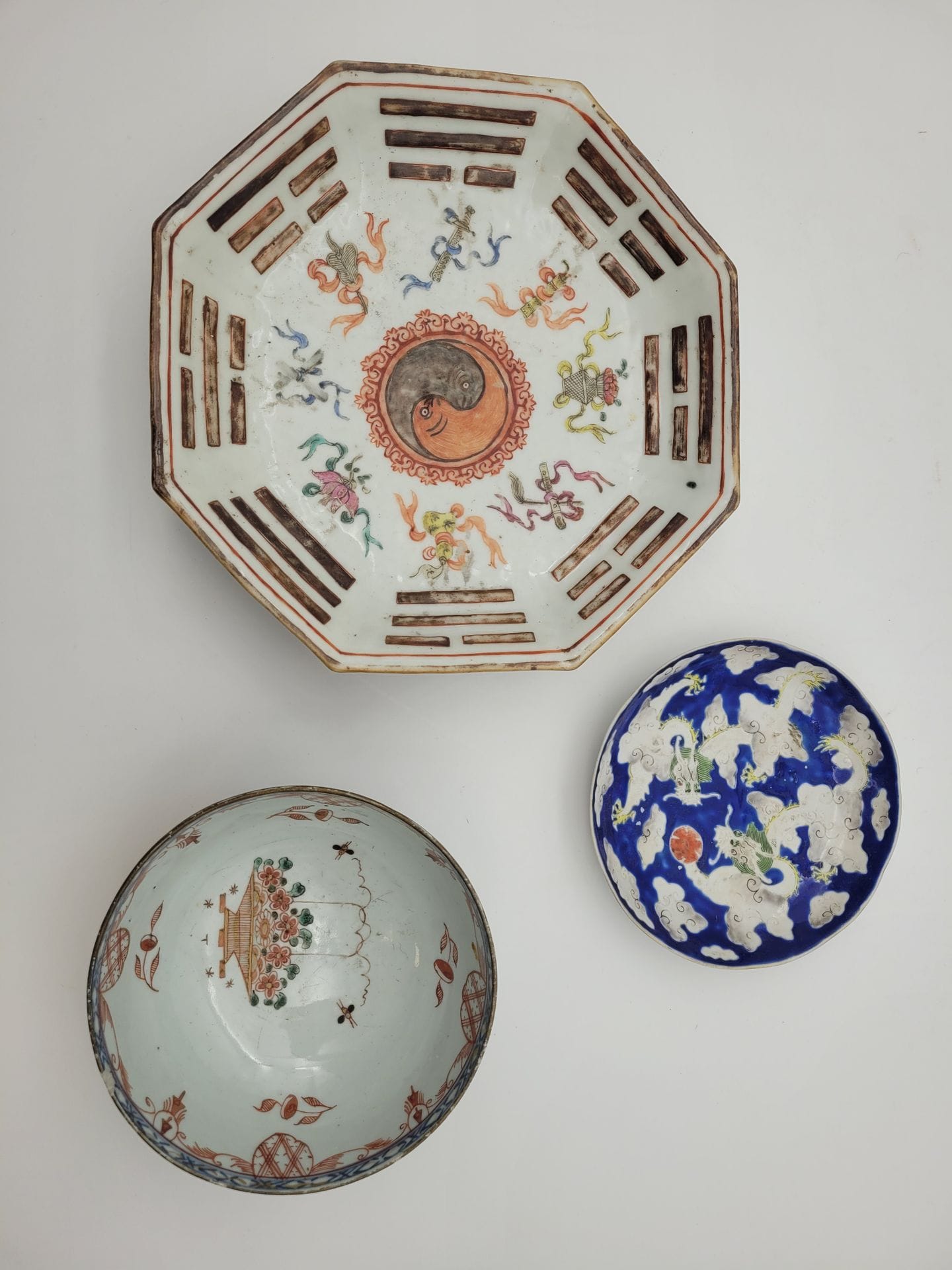 Set of three porcelain bowls, China, 18th-20th century
- 18th-century bowl with blue underglaze decoration, later overdecorated in red and gold. Diameter: 14.5 cm
- Octagonal pedestal bowl with central decoration of ying-yang and Buddhist symbols. Label ''Au vase étruste'' and mark under the base. L. : 24,5 cm
- Small dish decorated with dragons chasing the sacred pearl on a blue background. Mark under the base. Diameter: 14.5 cm
Minor accidents.