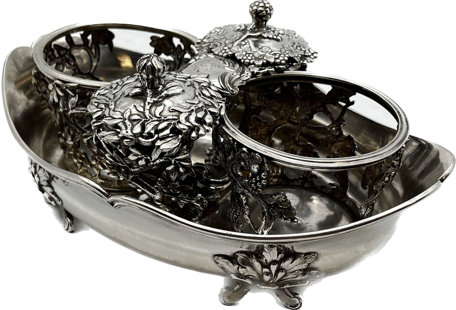 VERSAILLES 1756 - 1760
Oil and vinegar cruet in chased cast silver with stoppers. Shuttle-shaped, with fillet-molded rim, it stands on four cast feet chased with a shell on the reverse and olives on a leaf support. The flask, stopper and cork holders are decorated with vines for vinegar and olives for oil.
Engraved on the body and corkscrews are the arms of Joseph Rolin de Morel (Maurel) de Mons (1715 - 1783), bishop of Viviers in the Ardèche between 1748 and 1778.
Master goldsmith : Thomas MASSE
Weight: 1164 g - length: 23.9 cm - width: 15.2 cm
Condition: a vine frieze around the rim of a flask-holder is missing.