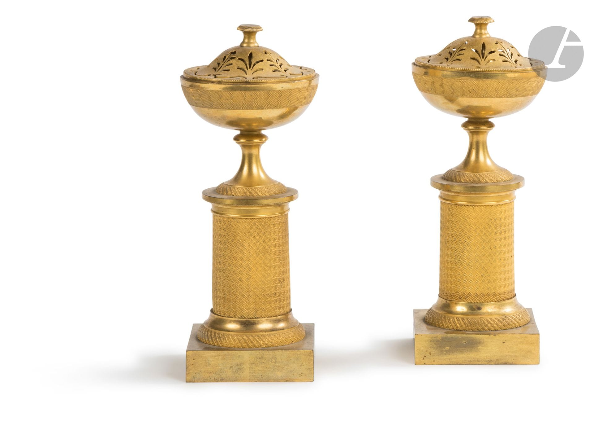 Paire de vases pot-pourri formant flambeau en bronze doré, les bobèches réversibles et le couvercle ajouré, reposant sur un fût de colonne à décor guilloché.
Époque Empire.
H. 22 cm