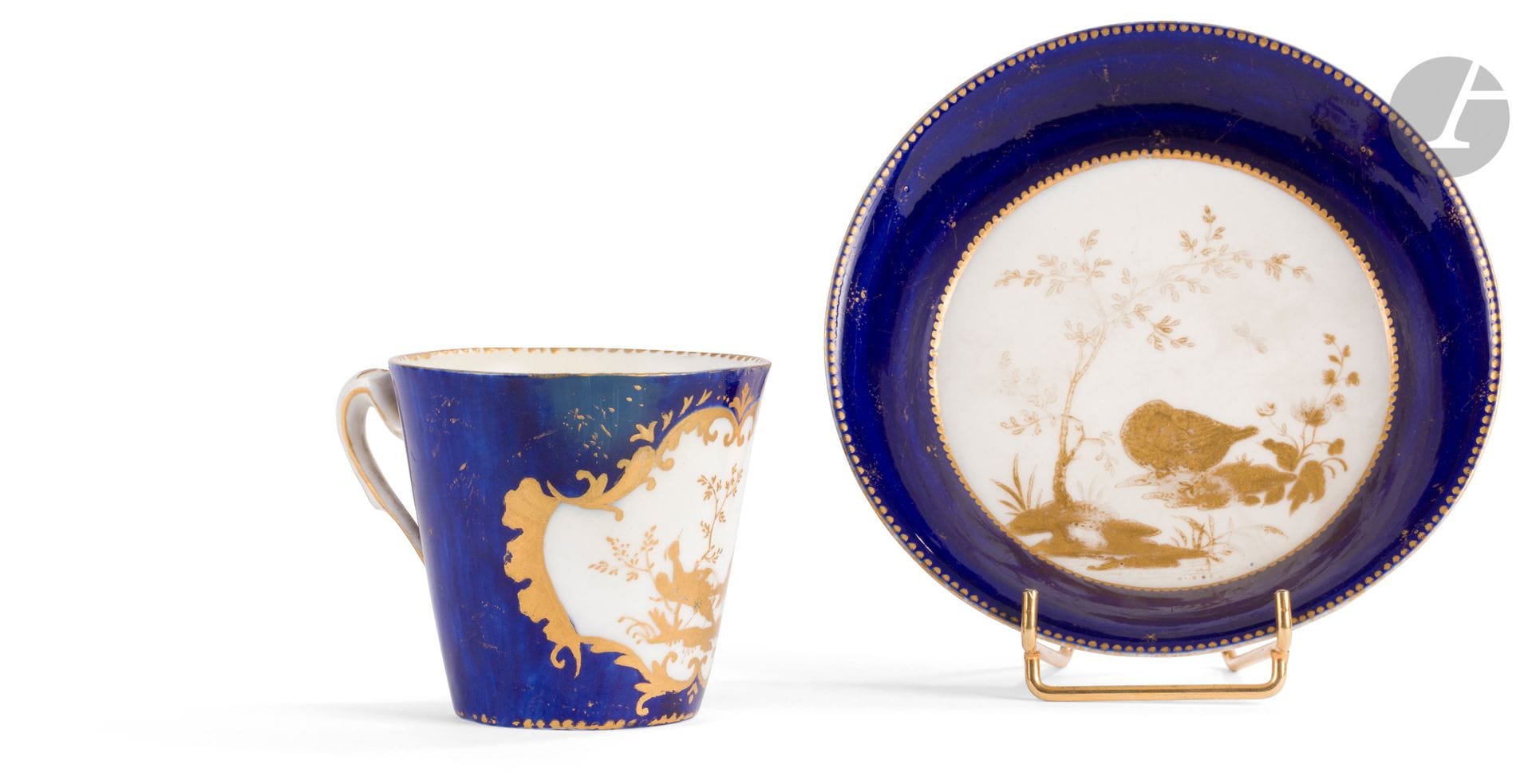 Vincennes
Gobelet à la Reine et sa soucoupe en porcelaine tendre à décor en or d'oiseaux sur terrasse sur fond bleu lapis, la réserve du gobelet encadrée de motifs d'ailes de chauve-souris en or.
Marqués : LL entrelacés, sans lettre-date.
XVIIIe siècle, vers 1752-1753.
H. 7 cm, D. 13 cm
Restaurations au gobelet, usures d'or.