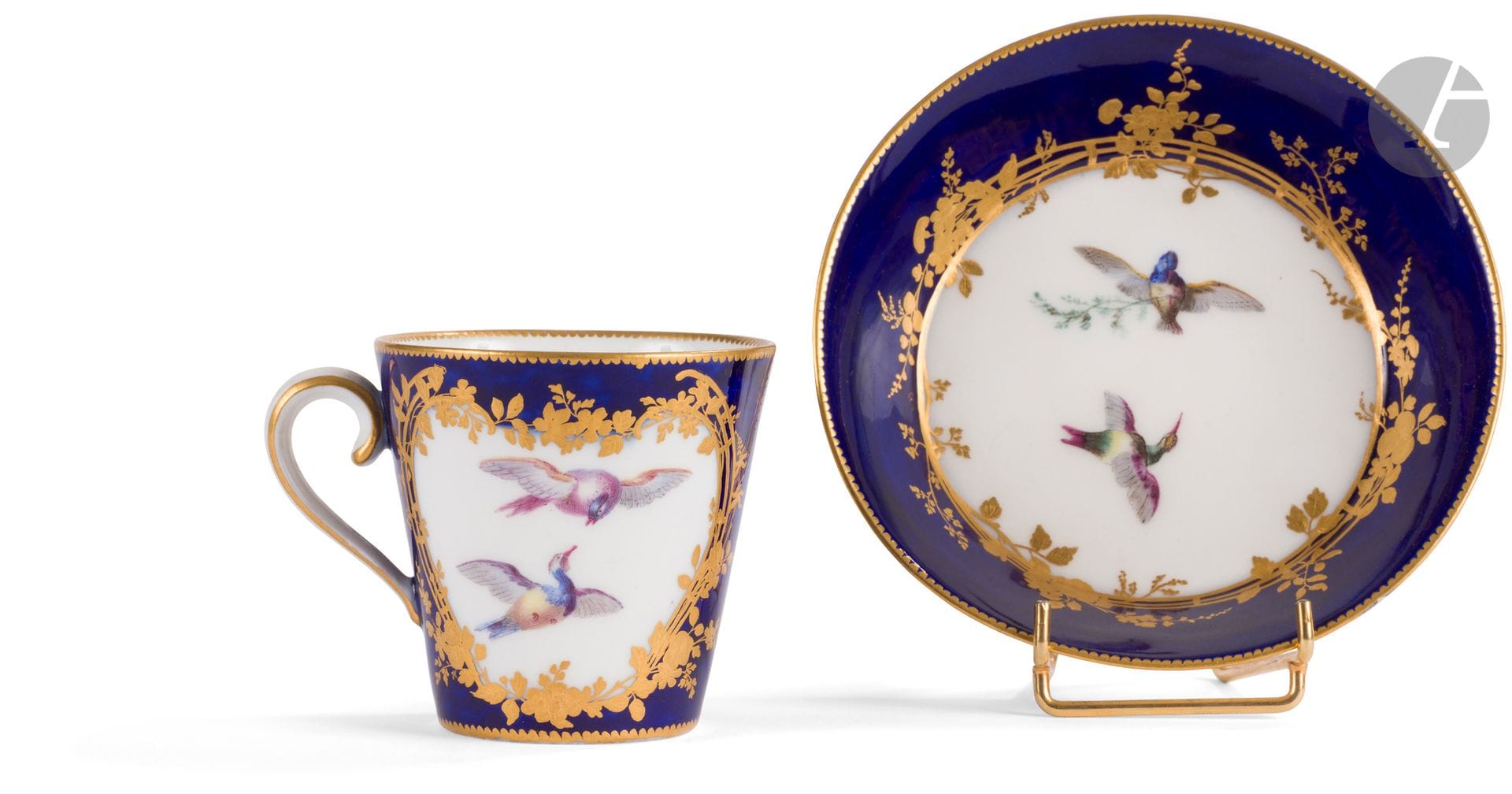 Vincennes
Gobelet à la Reine et sa soucoupe en porcelaine tendre à décor polychrome d'oiseaux en vol dans des réserves cernées de treilles et guirlandes de fleurs et feuillage en or sur fond bleu lapis.
La marque sous le gobelet effacée, la soucoupe marquée : LL entrelacés encadrés de trois points, lettre-date A pour 1754.
XVIIIe siècle, 1754.
H. 7 cm, D. 13 cm
La marque effacée sous le gobelet, un petit éclat restauré au revers de la soucoupe.