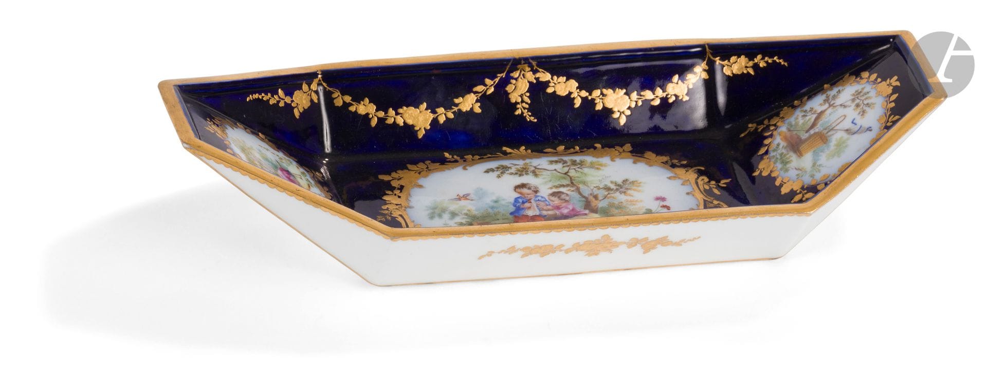 Vincennes-Sèvres
Plateau de déjeuner bateau en porcelaine tendre à décor polychrome de deux enfants dans un paysage et attributs champêtres dans des réserves cernées de rinceaux rocaille et fleurs en or sur fond bleu lapis.
Marqué : LL entrelacés, lettre-date C pour 1756, marque du peintre Vieillard.
XVIIIe siècle, 1756.
L. 28 cm
Un petit éclat restauré.
