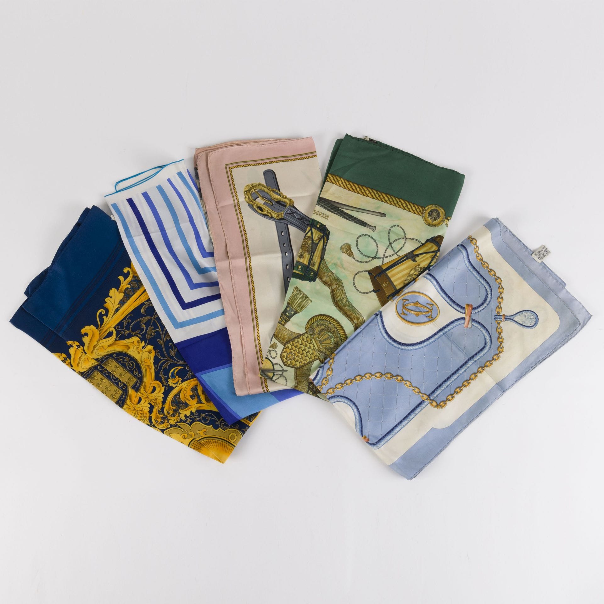 Lot de cinq foulards dont deux HERMÈS « Les Tambours » et « Harnais de cérémonie »(accidentés, décolorations, déchirures), un CARTIER, un DIOR