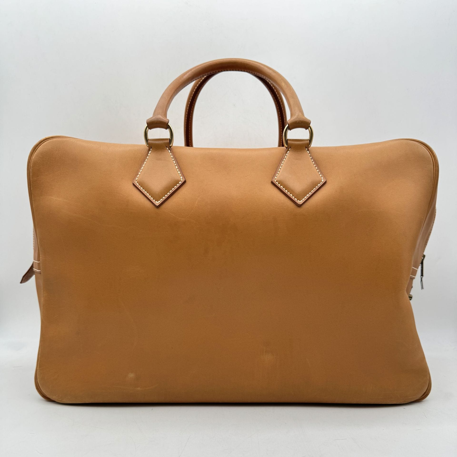 HERMÈS Paris Made in France 
Sac Plume de voyage en cuir caramel, garniture en métal doré, deux clés sous clochette, bandoulière
Année 1992
45 x 31 x 21 cm
(usures et taches aux angles, griffures et traces, clochette accidentée, languette du zip accidentée)