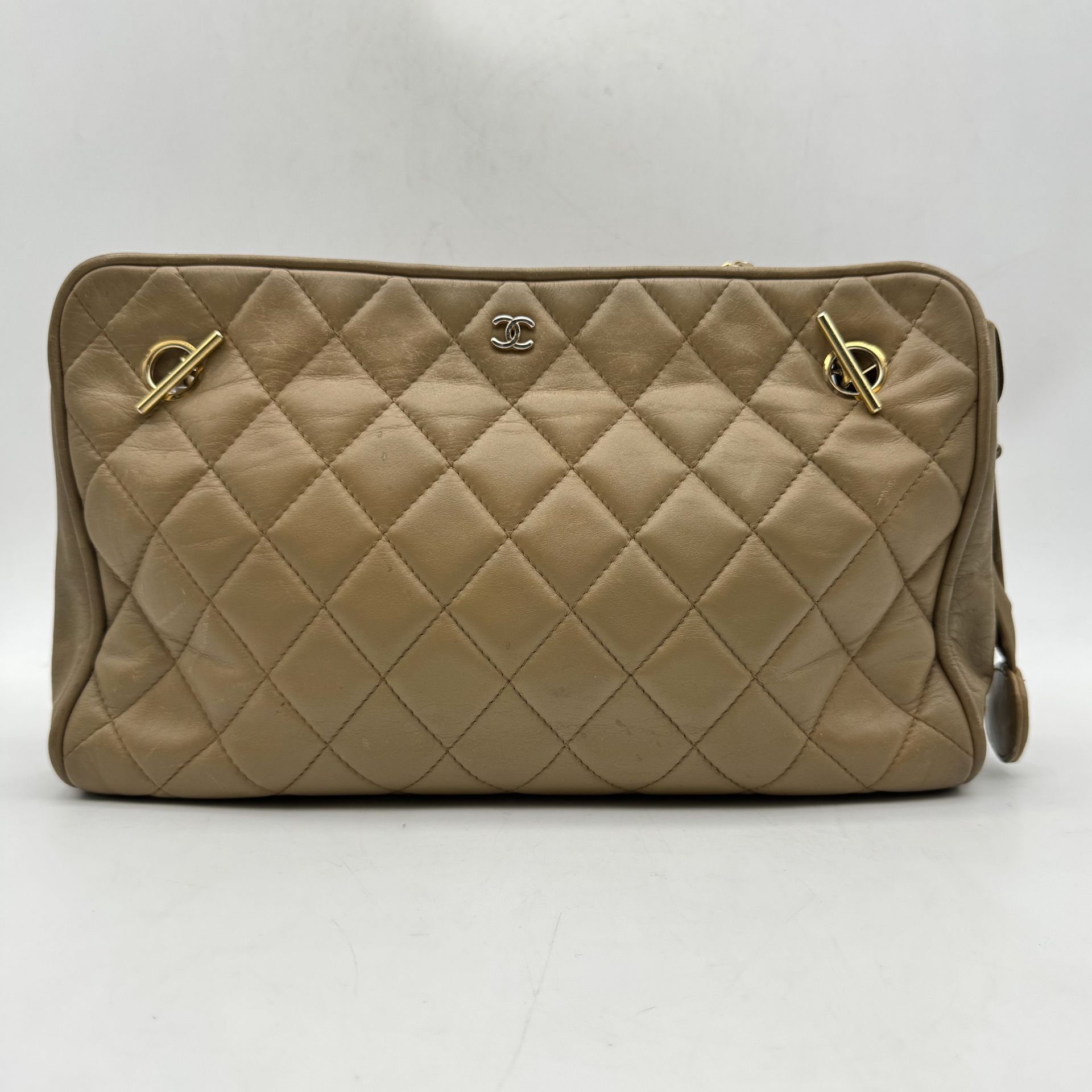 CHANEL Made in Italy
Beige leather bag, gilded metal trim, chain and leather handle, charm (worn, quilted, crumbled, zipper damaged)
Circa 1980
30 x 20 x 6 cm