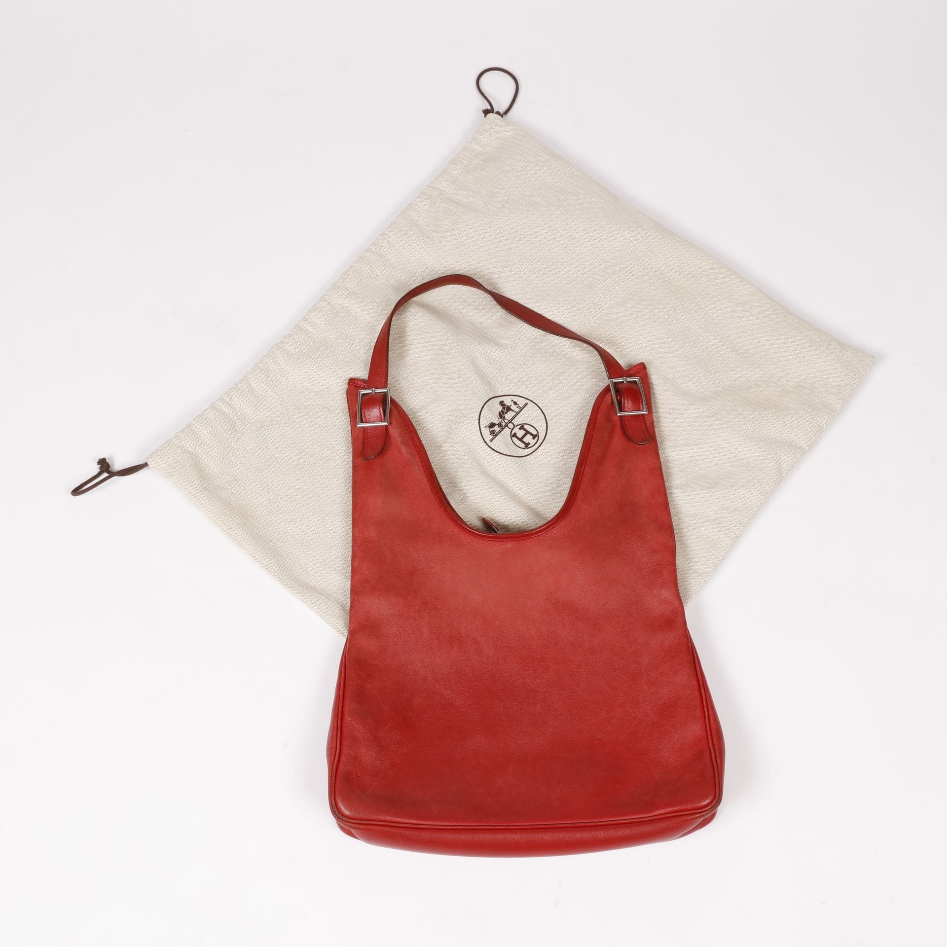 HERMÈS Paris Made in France
Sac Massai en cuir rouge, garniture métal argenté, doublure toile beige, dans sa housse
34 x 45 x 6 cm
(usures, traces, patine)