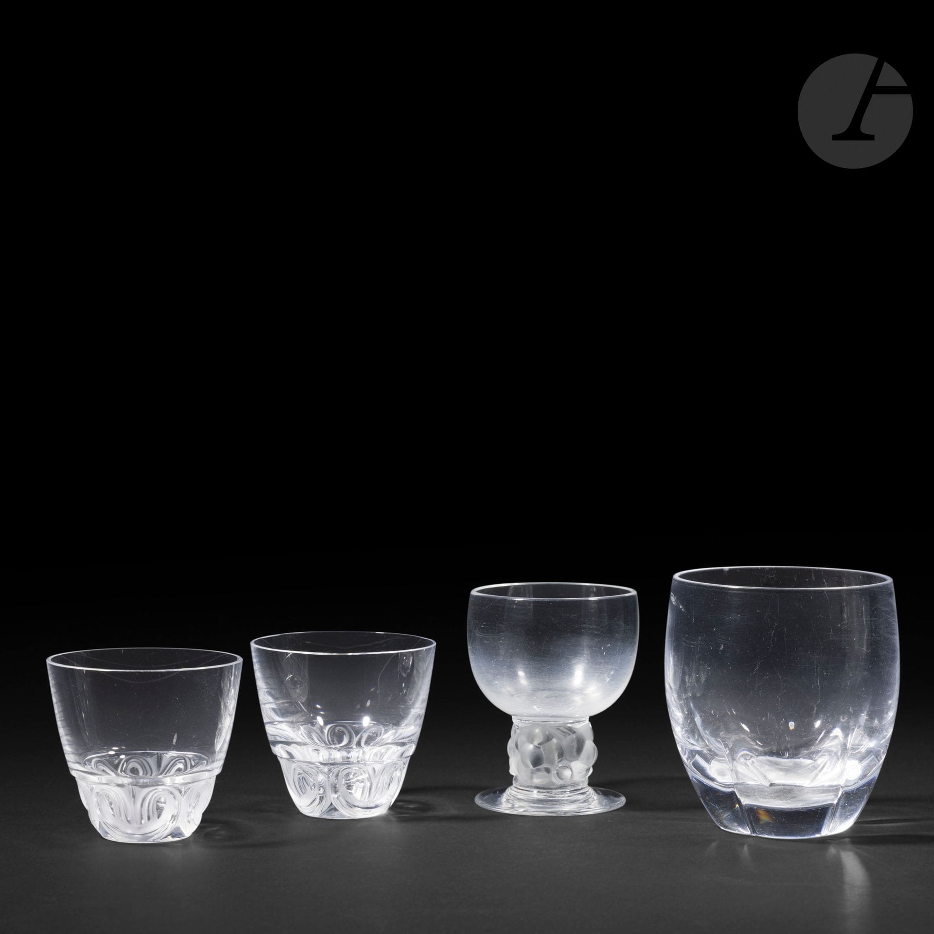 RENÉ LALIQUE (1860-1945) ET MARC LALIQUE (1900-1977) ET MAISON LALIQUE
Ensemble de 4 verres différents composé comme suit: 
- Thomery, le modèle conçu en [1931]
Un verre à Bordeaux n° 4 (Réf. Marcilhac 5255).
Épreuve en verre blanc soufflé-moulé pour le corps et moulé-pressé et, en partie satiné pour la base.
Signé R. Lalique France sous la base. 
- Highlands
Un verre à whisky.
Épreuve en cristal soufflé-moulé.
- 2 gobelets à décor de volutes en relief.
Épreuves en cristal soufflé-moulé et, en partie, satiné.
Chaque pièce signée Lalique ® France en lettres cursives, à la pointe, sous la base. 
Hauteurs: 9 – 10,2 cm – 7,1 cm