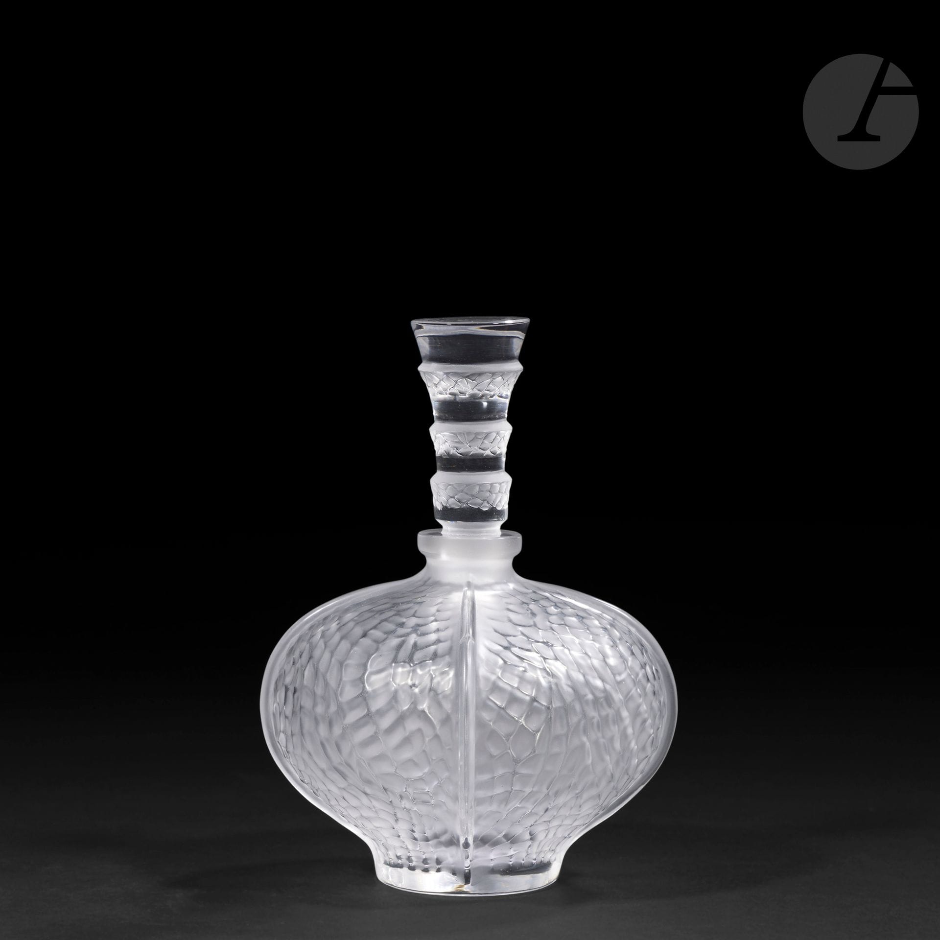 MARIE-CLAUDE LALIQUE (1935-2003) – MAISON LALIQUE
Éliselles
Flacon à parfum, le corps pansu à petit col annulaire au décor d’un nid d’abeilles, le haut bouchon circulaire à gradins. 
Épreuve en cristal soufflé-moulé pour la base et moulé-pressé pour le bouchon et, en partie, satiné.
Non signé.
Hauteur: 12 cm