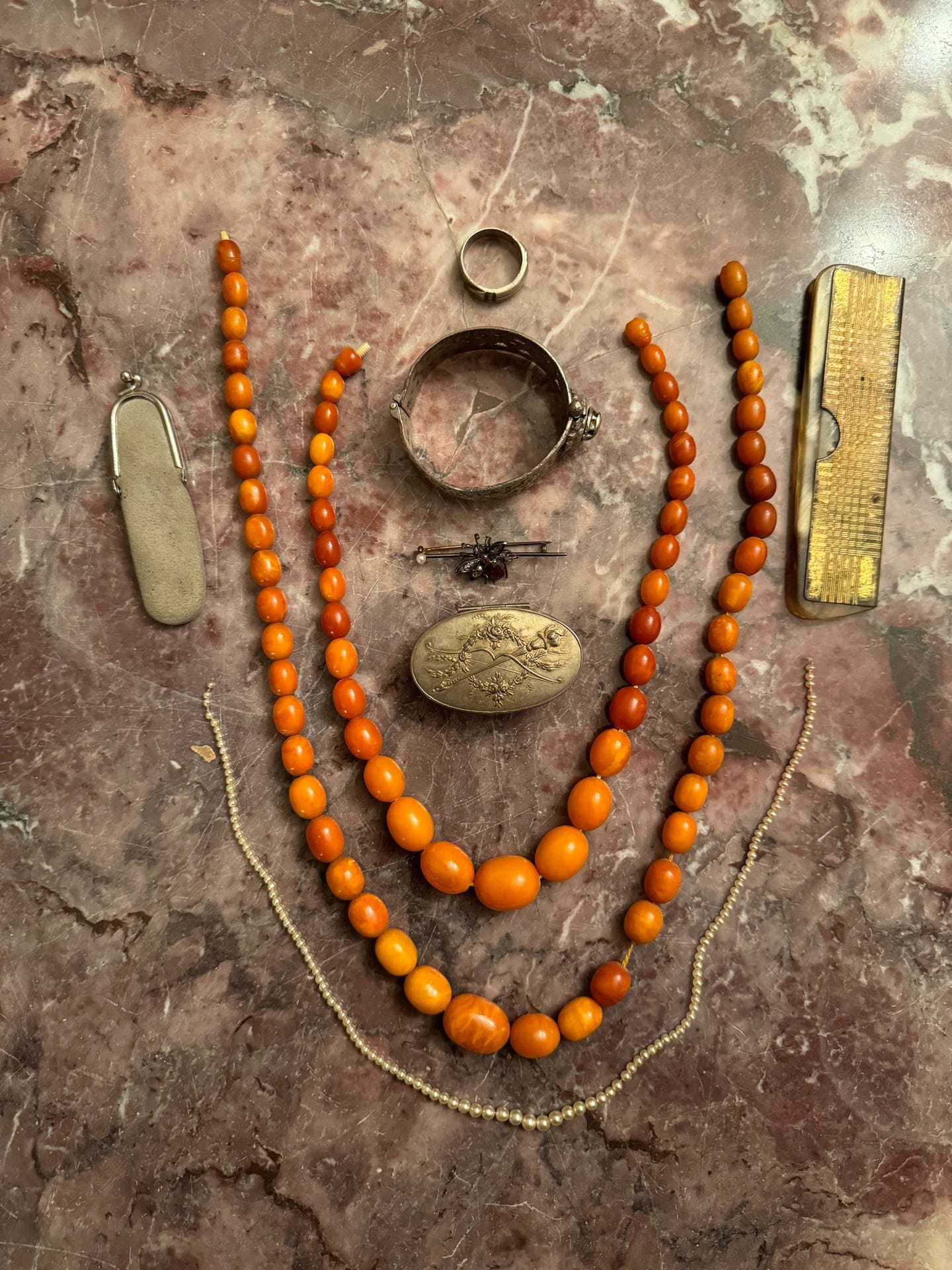 Lot de bijoux fantaisies comprenant un collier en résine imitant l’ambre, un collier de perles de culture, un petit couteau suisse, etc.