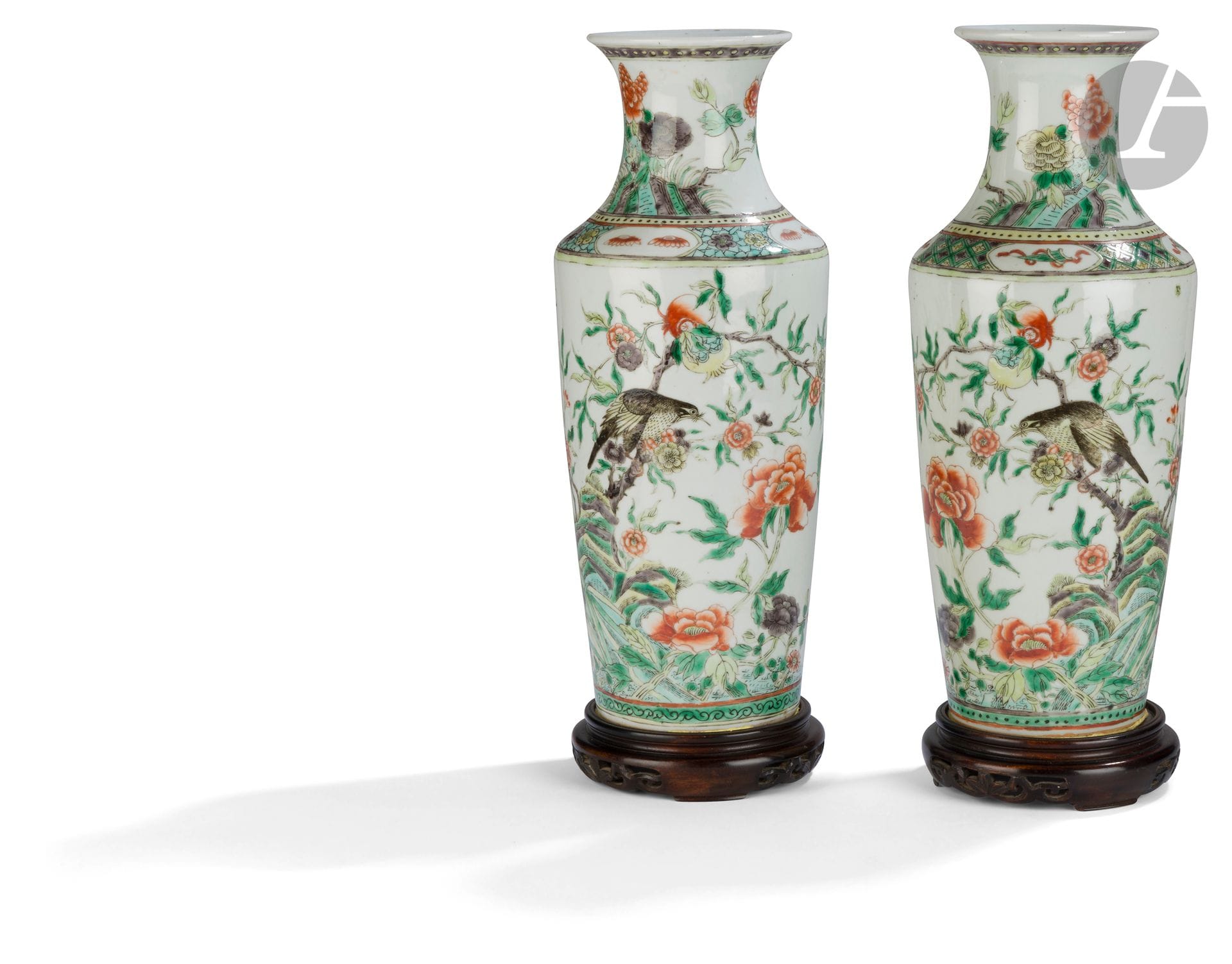 Paire de vases en porcelaine dans le style de la famille verte, Chine, XIXe siècle
De forme balustre, chaque panse est décorée d’un oiseau perché sur un arbre en fleur portant deux grenades qui prend naissance dans un rocher entouré de pivoines et fleurs diverses, autour des papillons en vol. L’épaulement de l’un est orné d’une frise dite « glace brisée » et de quatre médaillons à décor de fleurs, et celui de l’autre, d’une frise de svastika dans des losanges et de quatre médaillons à décor d’objets sacrés. Les cols évasés reprennent un motif de fleurs de pivoines et papillons. 
Hauteur : 35,5 cm
Les vases sont collés sur des socles en bois ajourés.