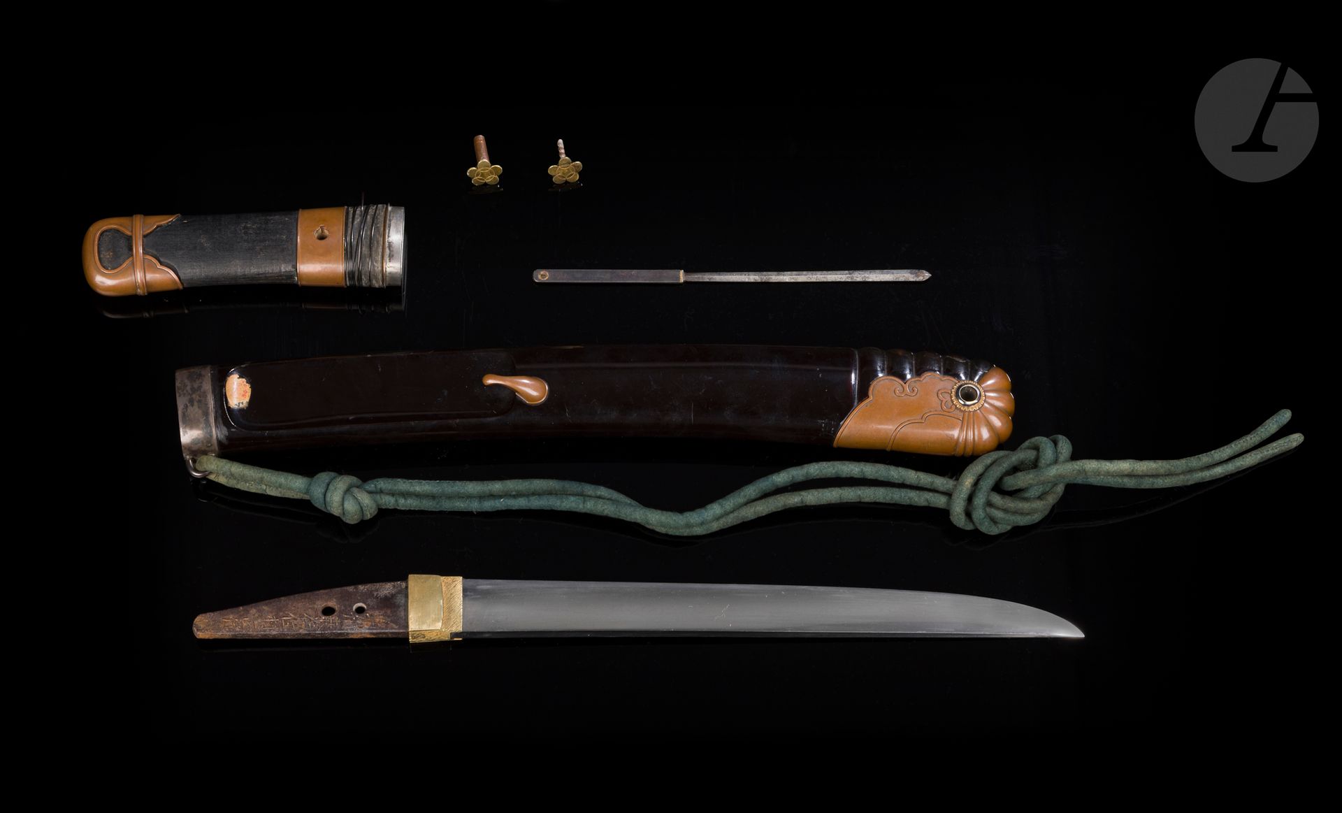 Aikuchi tanto, Japon : lame koto, époque Muromachi, XVIe siècle ; koshirae, époque Edo (1603-1868)
Lame hira zukuri, hamon suguha, ko itame hada. Nakago percé de deux mekugi hana, nakago signé Seishû Kuwana ju Muramasa saku - 勢州桑名住村作. Koshirae de type ebizaya constitué d’un saya laqué noir annelé au niveau du kojiri. Une partie des montures en suaka (kojiri, kaeri, kashira et sayadôgane), le reste des montures, fuchi et koiguchi en métal argenté. Tsuka en partie recouverte de fanons de baleine. Petit kozuka en fer à lame en forme de ken. Mekugi en cuivre doré à décor de mon en forme de fleur de prunier à cinq pétales. 
Nagasa : 25 cm