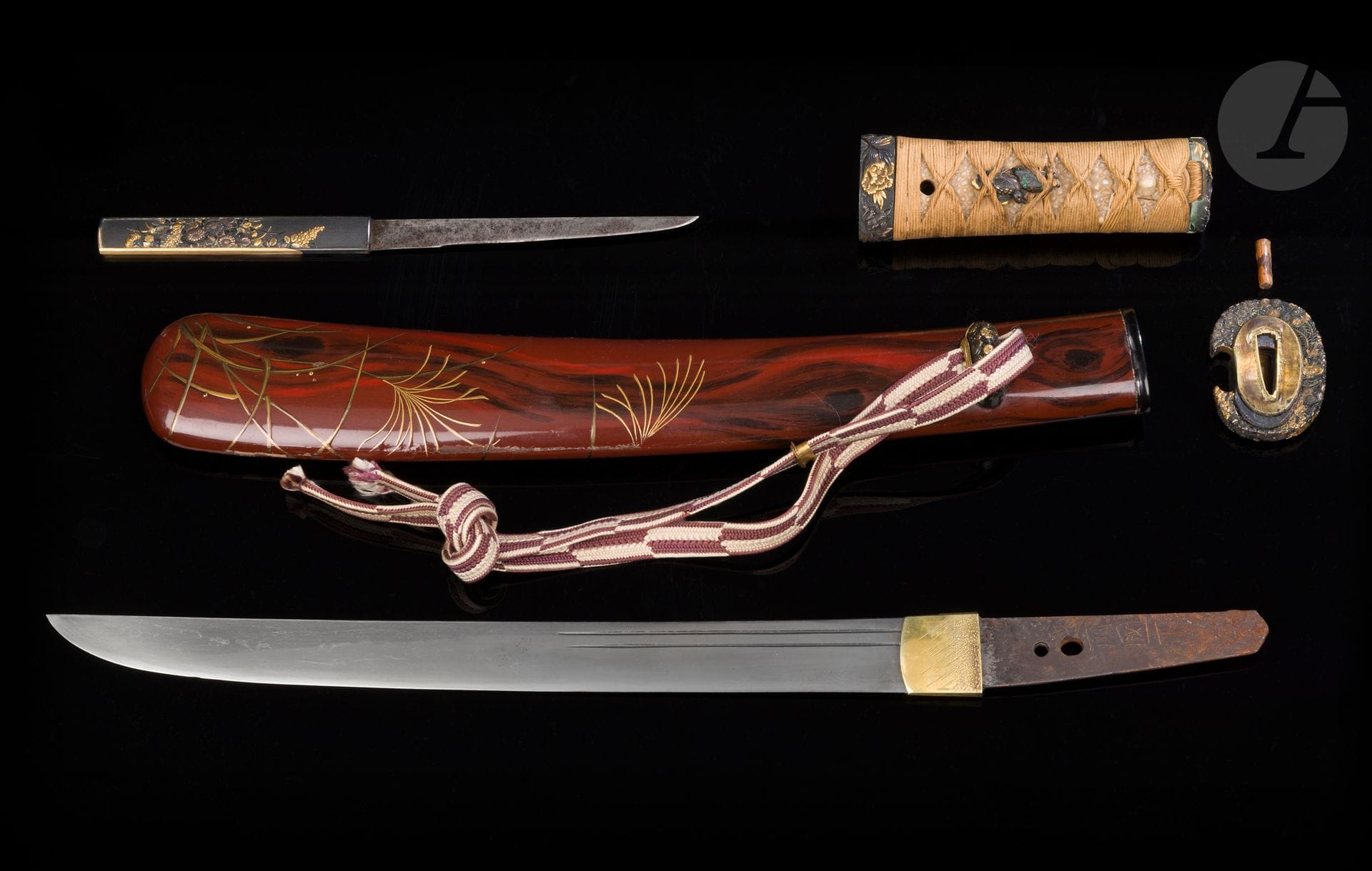 Tanto, Japon : lame koto, XVIe siècle ; koshirae, époque Edo (1603-1868)
Lame hira zukuri, hamon suguha, ko itame hada. Gorges futatsuji hi côté omote et Bo hi côté ura. Nakago percé de trois mekugi hana dont deux se chevauchent, signé 越前国下坂 - Echizen no kuni Shimosaka. Koshirae constitué d’un saya en laque brune imitant le bois à décor en hiramakie or de susuki (eulalies). Montures en suite avec fuchi kashira, tsuba, kurikata et kozuka en shakudo décorés en iroe takazogan de fleurs. L’arrière du kozuka traité en sogitsugi or et shakudo avec une signature ciselée Kifu Jû Naosada - 紀付住 直貞 avec kao. Fuchi signé Tsunenao 常直 (école Ichinomiya) avec kao, menuki à décor de perdrix.
Nagasa : 29,5 cm
Accidents et manques au saya. Défauts sur la lame.