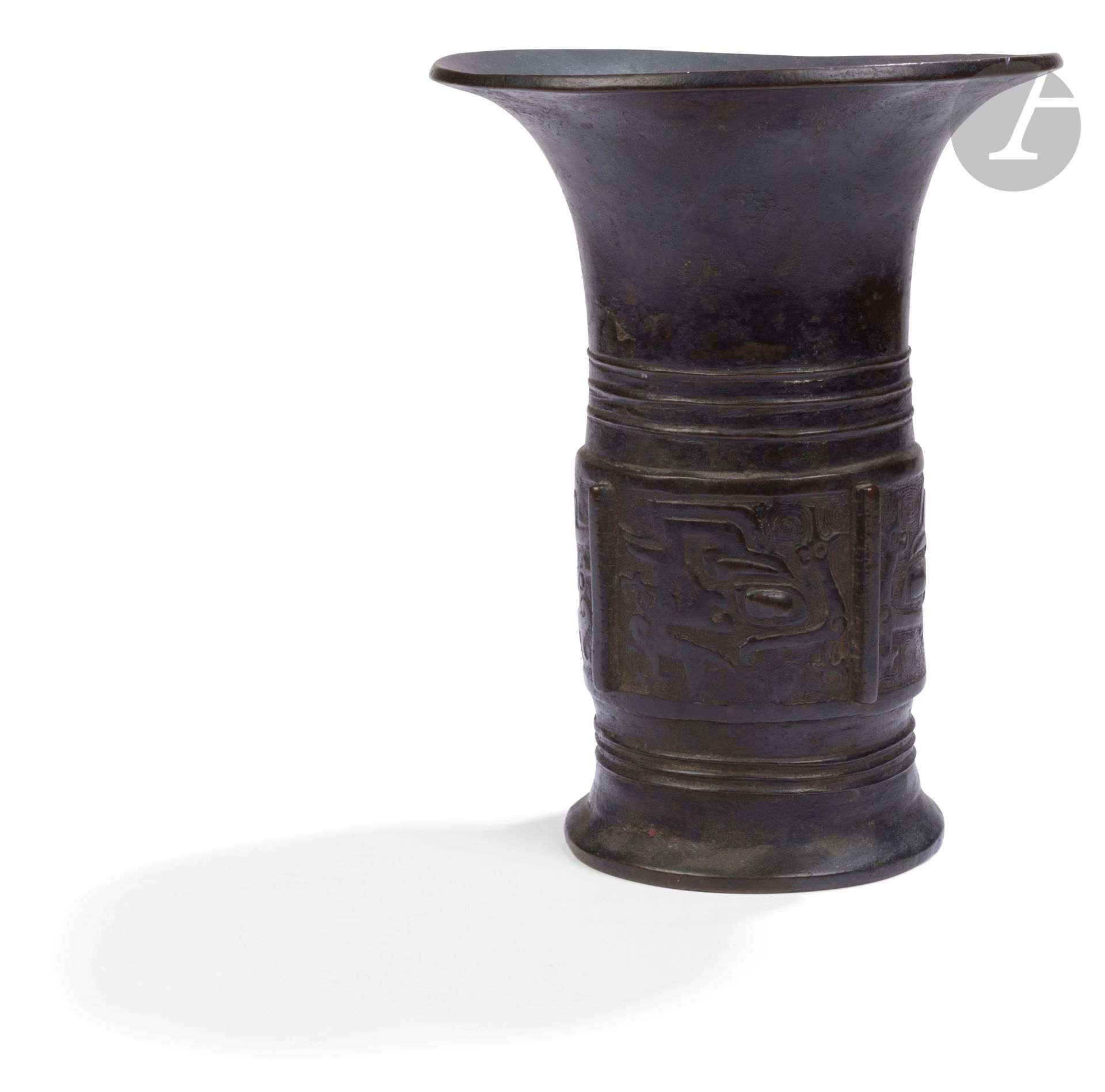Brown patina copper alloy gu vase, China, 17th century
Form inspired by archaic bronzes, decorated with a wide band chased in light relief with taotie masks and bird motifs known as niǎo wén. Three rings in relief adorn the base and bottom of the neck. The background is decorated with a diamond-patterned fishnet. 
Height: 24 cm
Repair to bottom.

Provenance: 
Knight Frank &amp; Rutley, London, September 14, 1962, lot n°111.