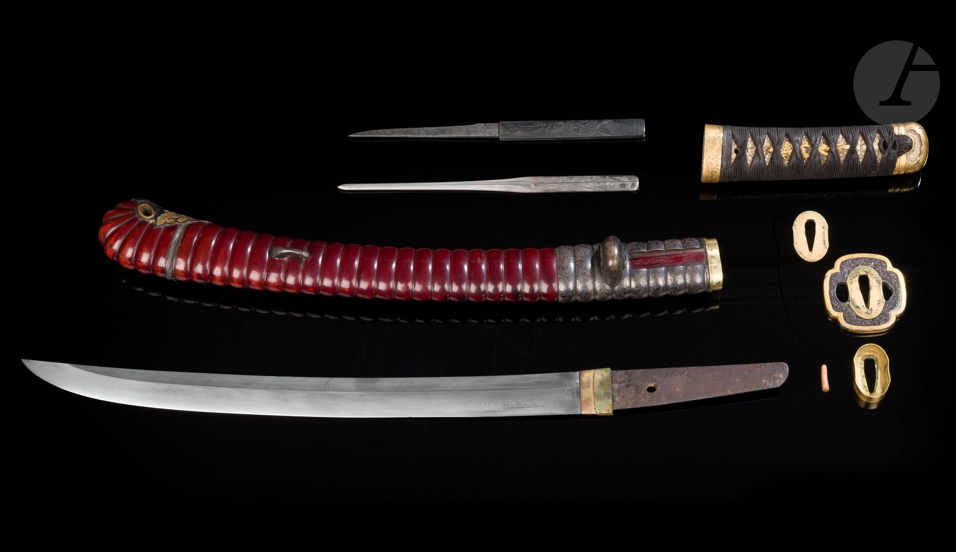 Tanto, Japan: koto blade, 16th century; koshirae, Edo period (1603-1868)
Shinogi zukuri naginata naoshi blade, hamon shoji midare, muji hada. Nakago pierced with a mekugi hana, signed Kanenobu saku - 兼信作. Ebizaya-type koshirae made of dark red lacquered ringed saya. Fuchi kashira decorated with chiseled clouds in katakiri bori on a gilded copper ishime background as well as the koiguchi. Menuki in gilded copper decorated with dragons. Tsuba, mokko gata form, in shakudo with nanako background chased in takaniku bori with flowers, gilded mimi, Minogoto school. Kaeri and kojiri in shibuichi, the latter partly gilded. Ringed shibuichi sayadôgane with chased foliage decoration, kogatana (kozuka) handle and wari kogaï in shibuichi with chased chrysanthemum decoration. Defects on the shinogi.
Nagasa : 36 cm