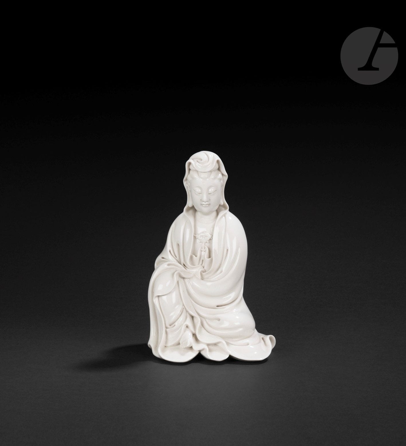 Guanyin en porcelaine blanc de Chine, Dehua, Chine, XVIIe siècle
Représentée assise, vêtue d’une robe à plis ouverte sur la poitrine, et parée d’un collier de perles au centre duquel se trouve une tête de champignon lingzhi. Le visage est serein, les yeux baissés et les cheveux sont rassemblés en un chignon couvert par le vêtement. Son front est paré au centre de l’urna. Dans le dos figurent deux sceaux : un sceau de forme double-gourde moulé avec l’inscription en zhuanshu « He Chao Chun » - 何朝春 et un sceau carré moulé avec l’inscription en zhuanshu « Xuande » - 宣德.
Hauteur : 20 cm

Potier de Dehua, He Chao Chun est le frère de He Chao Zong.