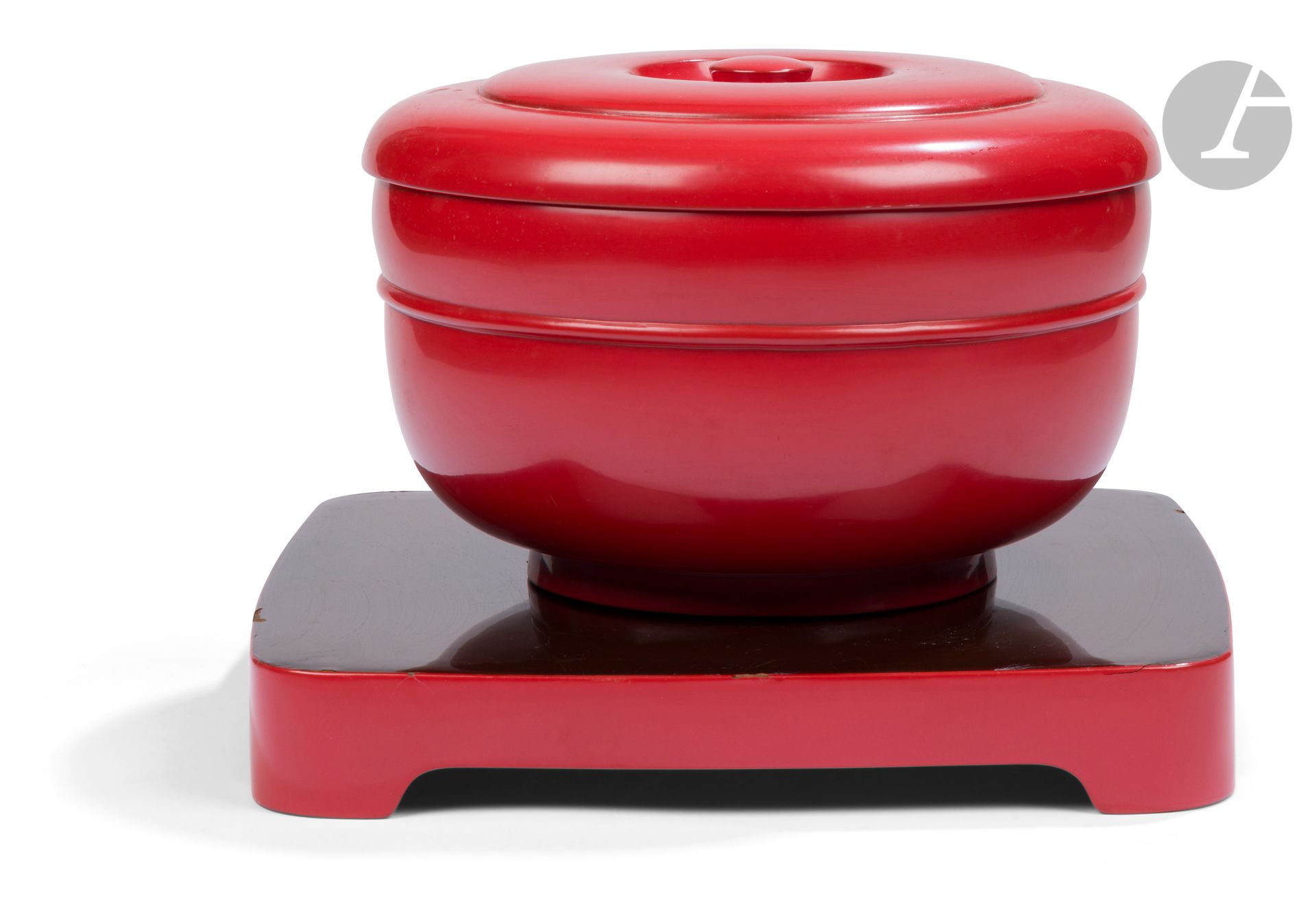 A round lacquered wood box and tray, Japan, Meiji-Taisho period
Cylindrical box of the o hitsu type with a flat grip lid, standing on a small circular foot. Shu nuri (red) lacquered, while the underside is black lacquered. It rests on a square tray with a rounded edge and four feet, the top of which is black lacquered and the rest shu nuri lacquered.
H. box: 16 cm; diam.: 24 cm; tray: 30.3 x 30.3 cm
Chips and scratches.