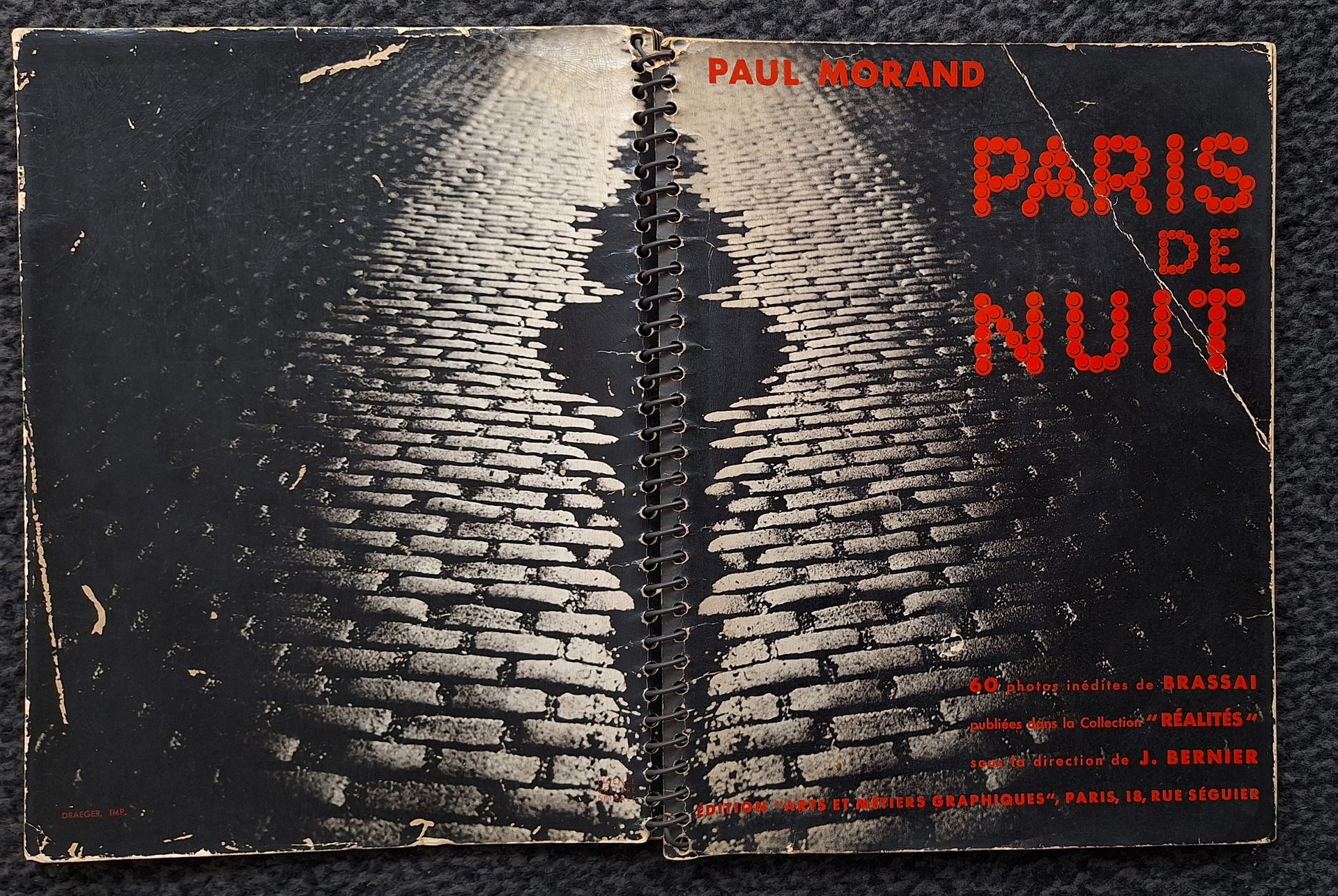 BRASSAÏ (Gyula Halasz, dit) (1899-1984)
Paris de Nuit.
60 photos inédites de Brassaï publiées dans la collection  Réalités  sous la direction de J. Bernier.
Éditions Arts et Métiers Graphiques, Paris, 1933.
In-8 (25 x 19 cm). Édition originale. Photographies imprimées en héliogravure. Reliure à spirale. Couverture laquée, illustrée et titrée en rouge. Couvertures avec défauts; intérieur très bon. 
Ref. Parr & Badger, I, p. 131 ; Hasselblad, pp. 110-111.