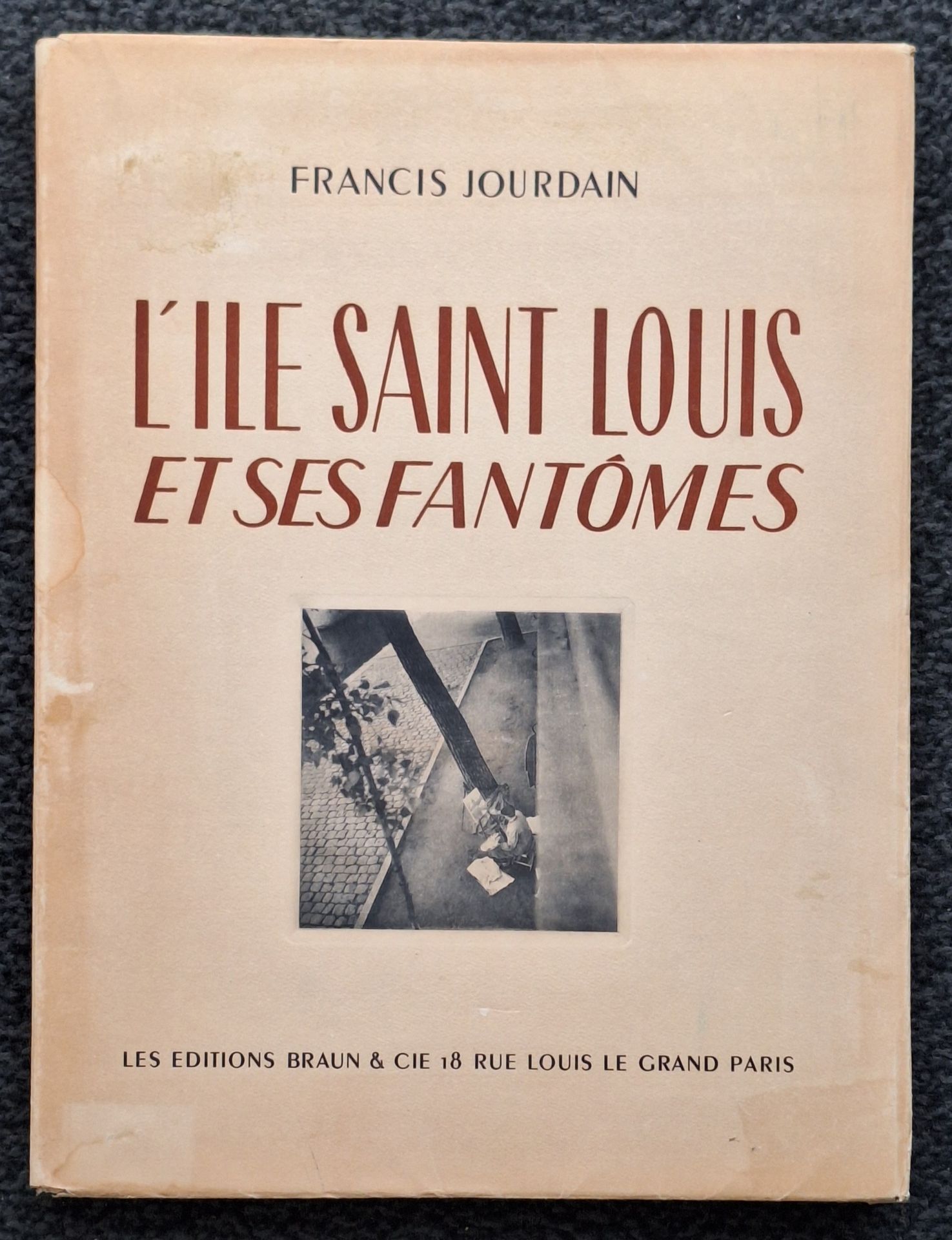 DUVAL, RÉMY (1907-1984)
L'Île Saint Louis et ses fantômes.
Les Éditions Braun & Cie, Paris, 1946.
In-folio (37 x 28 cm). Édition originale, tirée à 750 exemplaires numérotés. Exemplaire Hors-Commerce. Texte de Francis Jourdain. Photographies de Rémy Duval. 20 pp. de texte, suivies de 15 photographies reproduites en héliogravure, encrées à la main à l'unité. Cartonnage rigide sous jaquette illustrée rempliée. Intérieur du livre en parfait état ; couverture légèrement brunie et avec une mouillure.
Rémy Duval a été l'assistant de Laure Albin-Guillot.