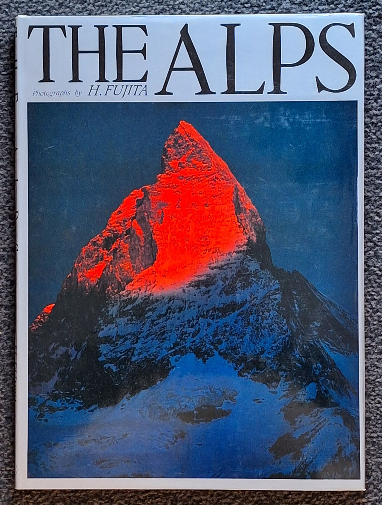 FUJITA, HIROKI (1939-2012)
The Alps.
Gyosei, 1986.
Very large in-4 (47 x 34 cm). First edition. 96 pp. Full- and double-page color photographs. Titled boards in filled illustrated dust jacket.