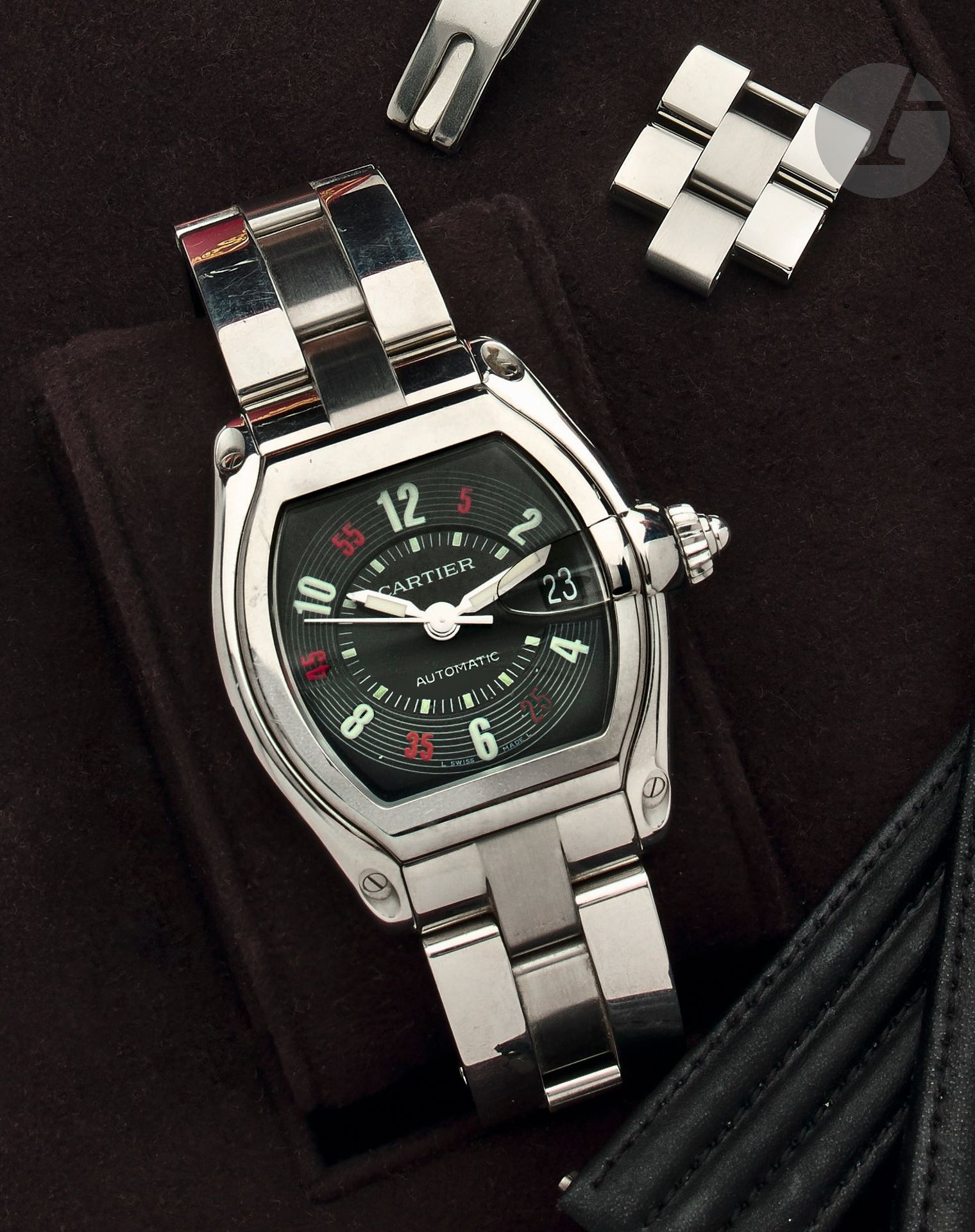 CARTIER
ROADSTER. REF. 2510.
VENDUE EN 2002
Montre bracelet en acier.
Boîtier: tonneau, fond plein vissé.
Cadran: noir, index chiffres arabes luminescents pour les heures et rouges pour les minutes, seconde centrale, guichet dateur. 
Mouvement: automatique.
Bracelet: acier, boucle déployante invisible, signée.
Cadran, boîtier et mouvement signés. 
Numérotée 387031CD.
Dim.: 44 x 37mm 
Avec: écrin-coffret, certificat, mode d’emploi, set de nettoyage, un maillon supp., un bracelet en cuir et une boucle déployante en acier, signée.