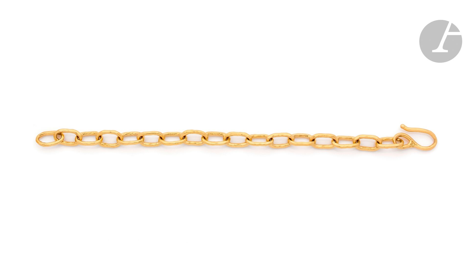 JEAN MAHIE pour CARTIER
Bracelet en or 21K (916) martelé composé de maillons ovales, le fermoir formant un crochet. Monogrammé. Travail français des années 1980. Longueur: 19,6cm environ. Poids: 28,6g
 A Jean Mahié bracelet
 Jean Mahié est le nom à deux visages d’une grande maison de bijoux: ceux de Jacline et de son beau-père Jean-Marie Mazard. Rien ne semblait prédisposer Jean-Marie à se tourner vers ce domaine, homme d’affaires multi-millionnaire propriétaire des magasins Prénatal. Il cultive néanmoins la passion du bijou et décide finalement de s’y consacrer entièrement à l’aube de ses 60 ans. Jacline, sculpteur, le rejoint et cette collaboration va donner corps à Jean Mahié dès 1969. 5 ans et 15kgs d’or plus tard, la Maison connaît un immense succès dans le monde entier. Les bijoux sont uniques, conçus comme de véritables sculptures, l’or 22K dont ils sont faits marque leur singularité. Louis Arpels remarque ce travail et propose d’exposer dans les vitrines de la Place vendôme quelques pièces, Cartier fera de même par la suite. Cette formidable publicité contribue à faire connaître et asseoir une réputation. Jacline s’installe finalement à New York tandis que son beau-père se retire à Genève. Elle développe son travail, enrichit ses modes d’expression et gagne le cœur des collectionneurs qui n’hésitent pas à lui acheter des dizaines de pièces. Son credo était d’être « forgeron d’or » plutôt que fabricante de bijoux, chaque maillon était frappé de 100 coups de marteau, plus qu’un travail, un sacerdoce au service de l’art.