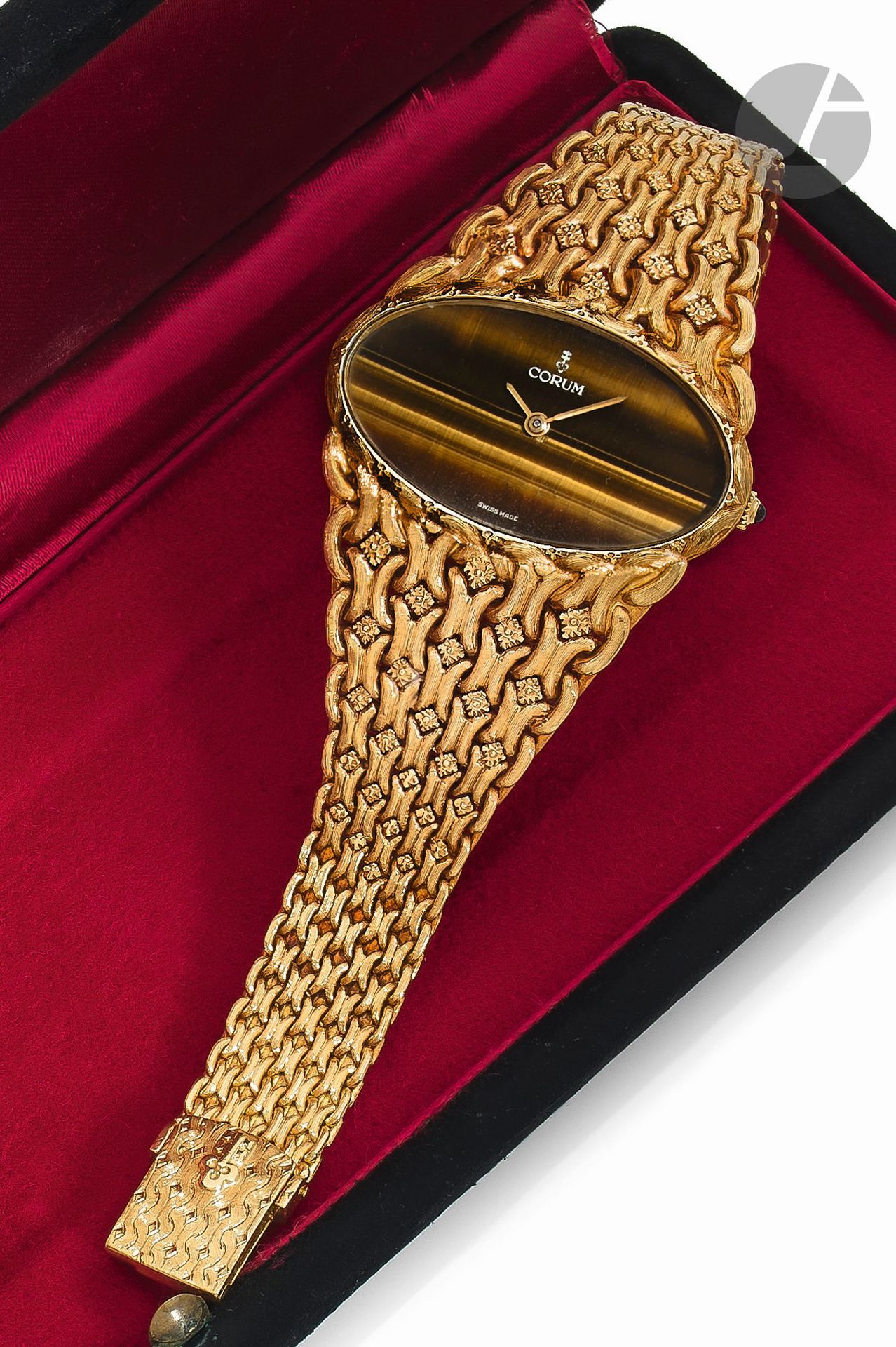 CORUM
ŒIL DE TIGRE
ANNÉES 70
Montre bracelet de dame en or jaune 18K (750) et œil de tigre.
Boîtier: large, ovale
Cadran: œil de tigre
Mouvement: mécanique, N°113883.
Bracelet: intégré en or jaune, maillons travaillés, boucle simple siglée Corum.
Cadran, boîtier et mouvement signés. 
Numérotée 1X 5231.
Diam.: 39mm 
Tour de poignet: 17,5cm.
Poids brut: 88,16g
Avec: écrin Corum.