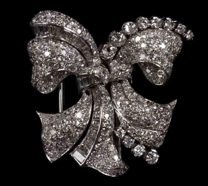 Broche noeud en platine, entièrement sertie de diamants ronds et baguettes. (Un diamant détaché, petit accident : deux soudures à refaire). Poids brut : 19 g.
