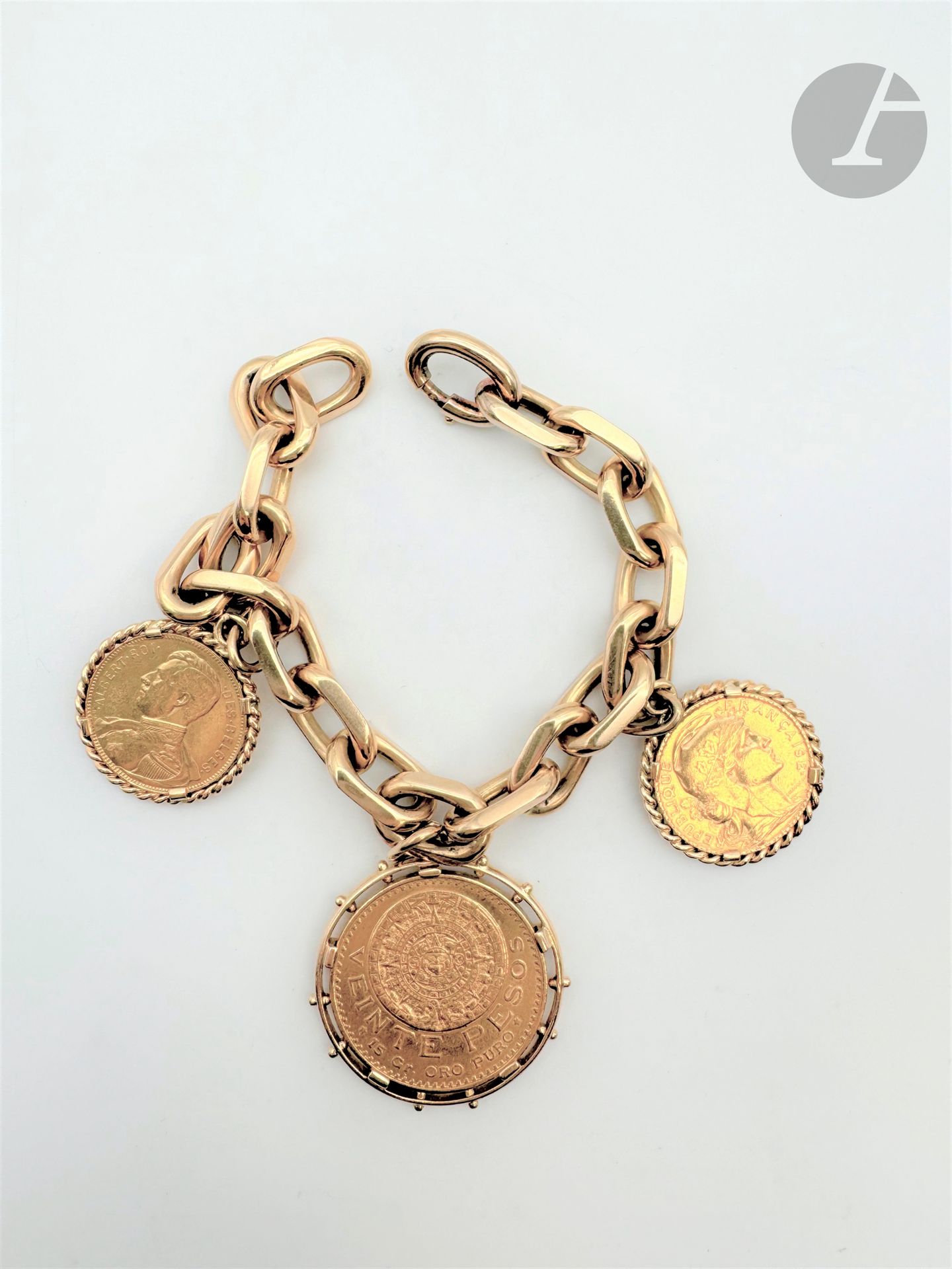 Bracelet maille forçat en or 18K (750), retenant en pampilles : une pièce de 20 Francs datée 1905, une pièce de 20 Pesos datée 1919 et une pièce de 20 Francs belge datée 1914. Traval français. Longueur : 19,5 cm environ. Poids brut : 102,2 g