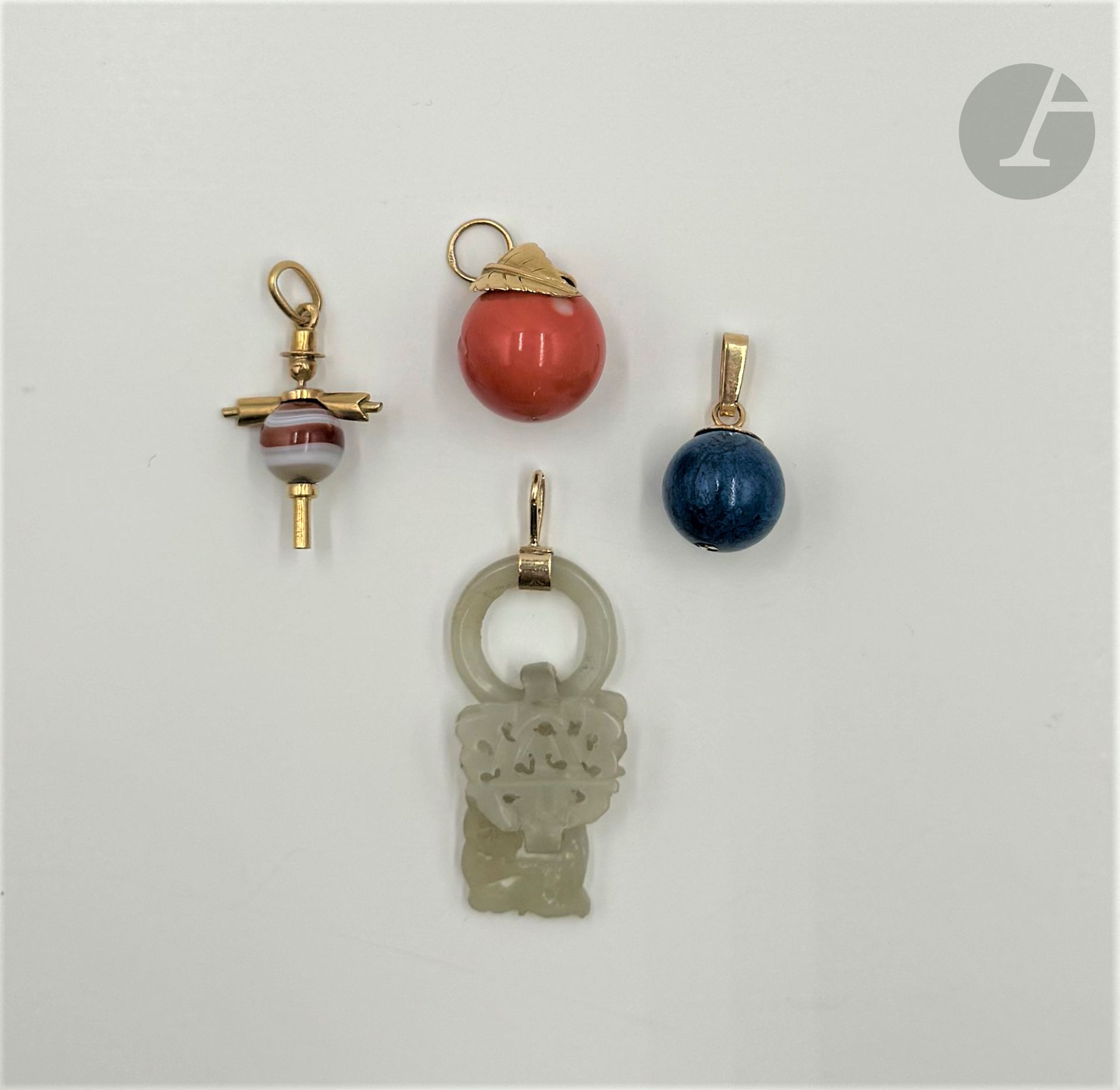 * Suite de quatre pendentifs : les 3 premiers montés en or 18K (750), agrémentés d'agate, de corail ou de jade ; le 4ème orné d'une sphère de pierre dure bleue montée en or 14K (585). Poids brut or 18K : 12,4 g ; poids brut or 14K : 3,3 g (usures et égrisures)